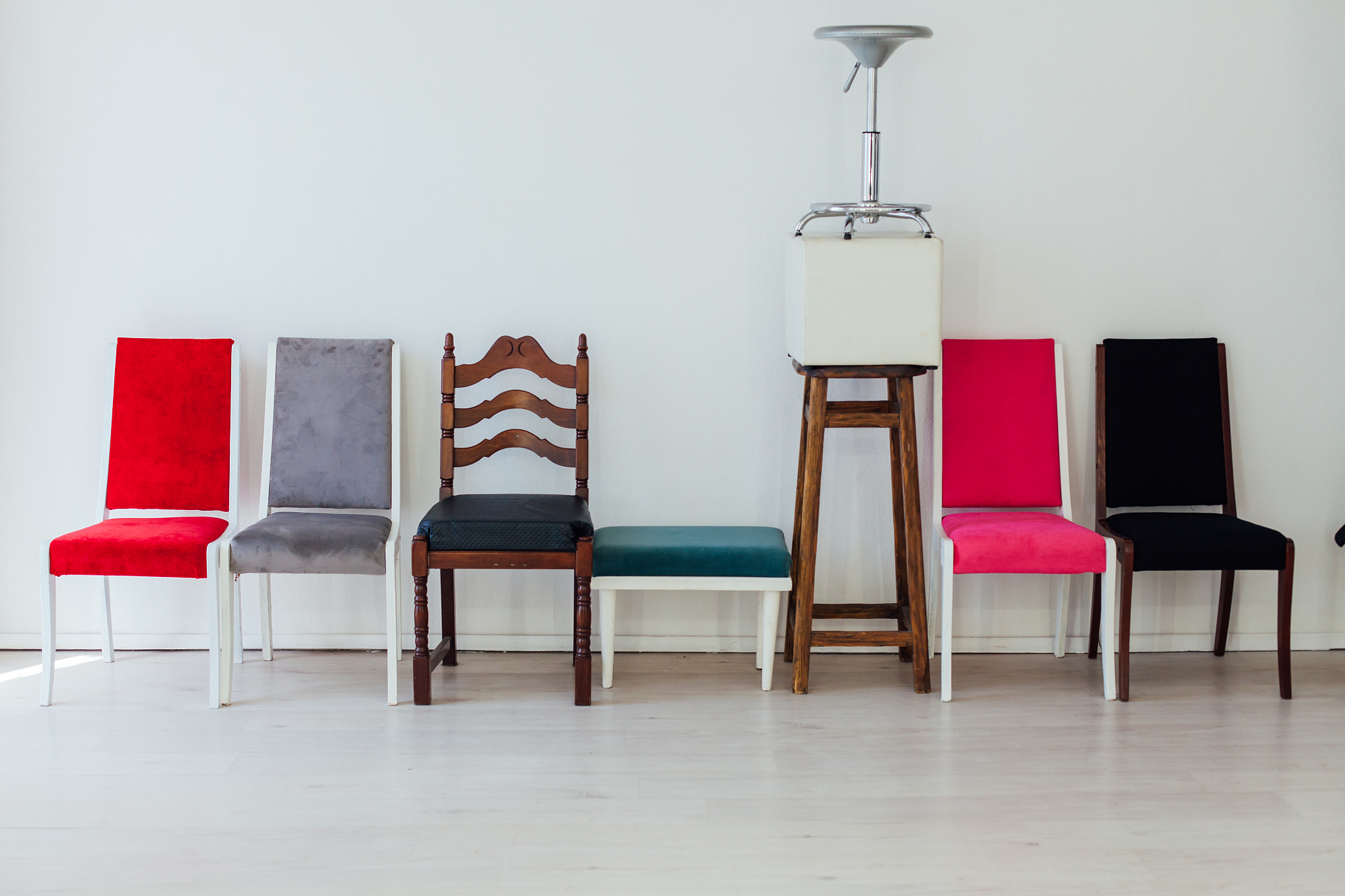 many different chairs stand in the white room