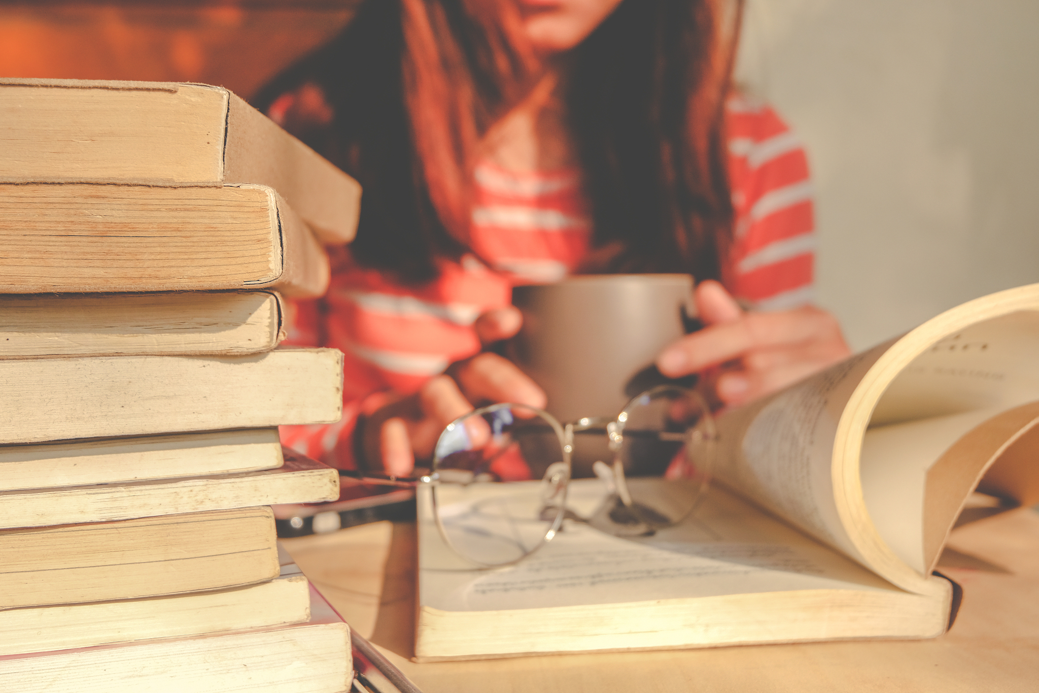 close-up of woman reading books while having coffee at table