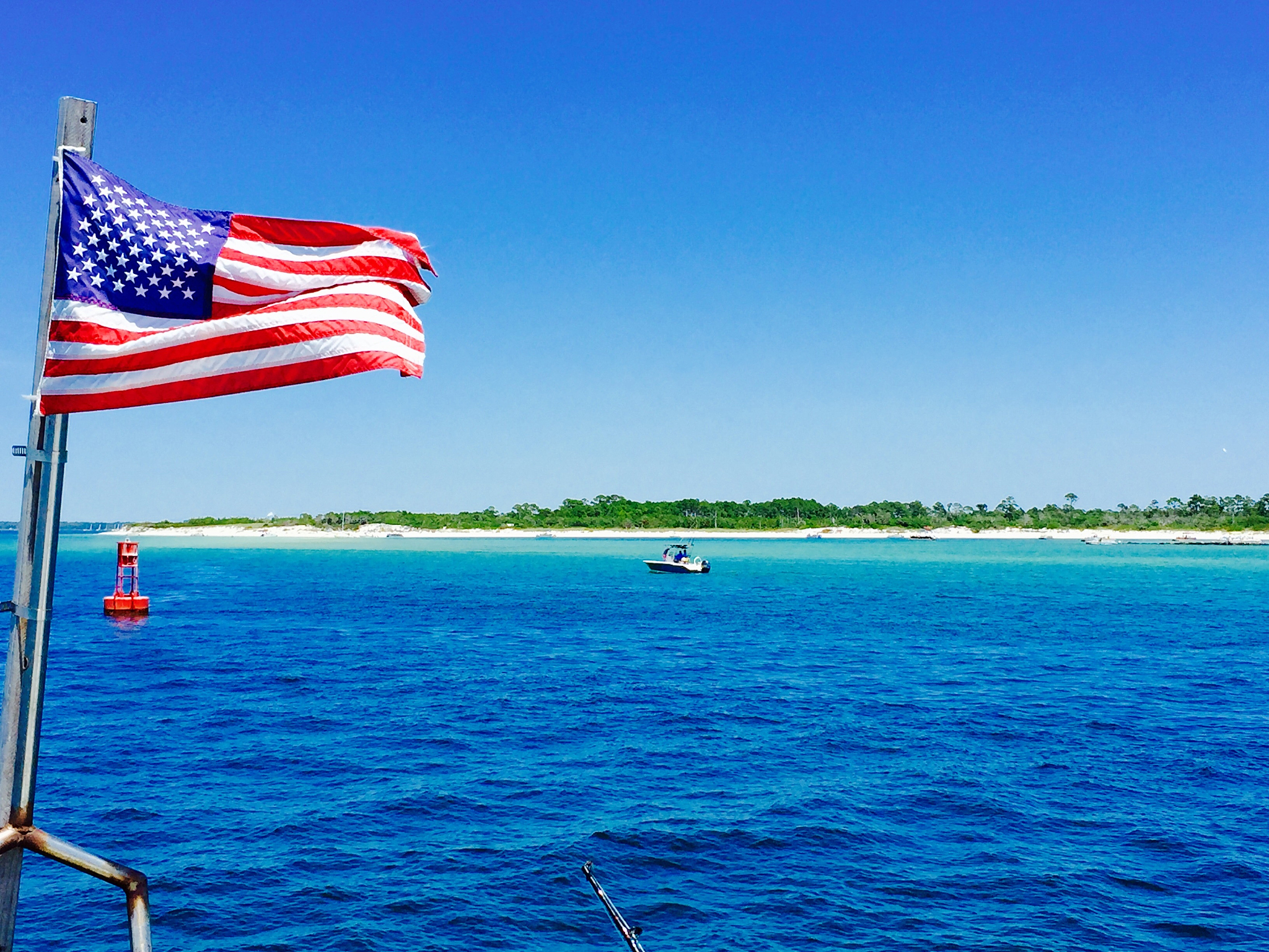 american flag flying by sea against clear blue sky