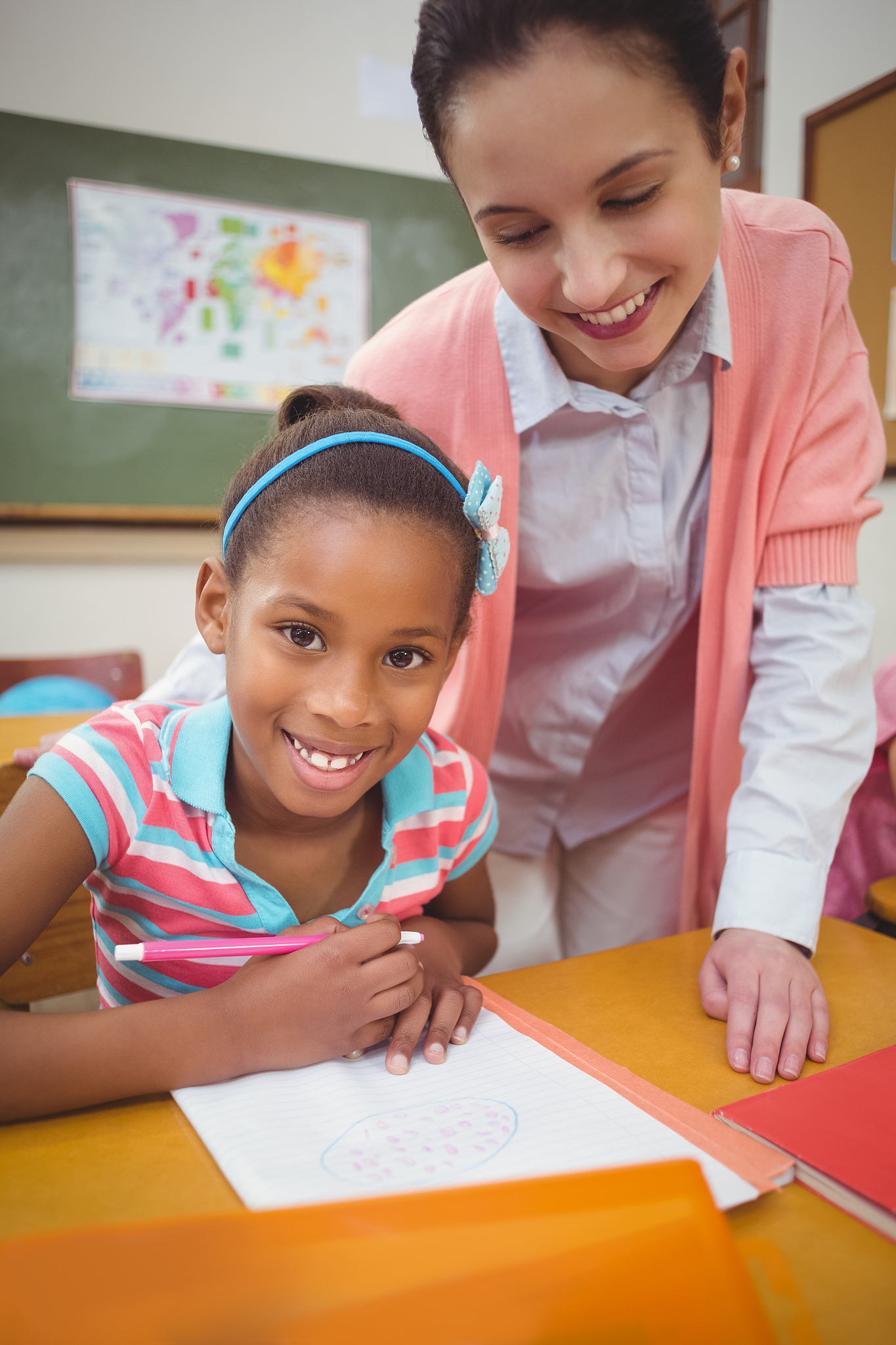 pupil and teacher at desk in classroom