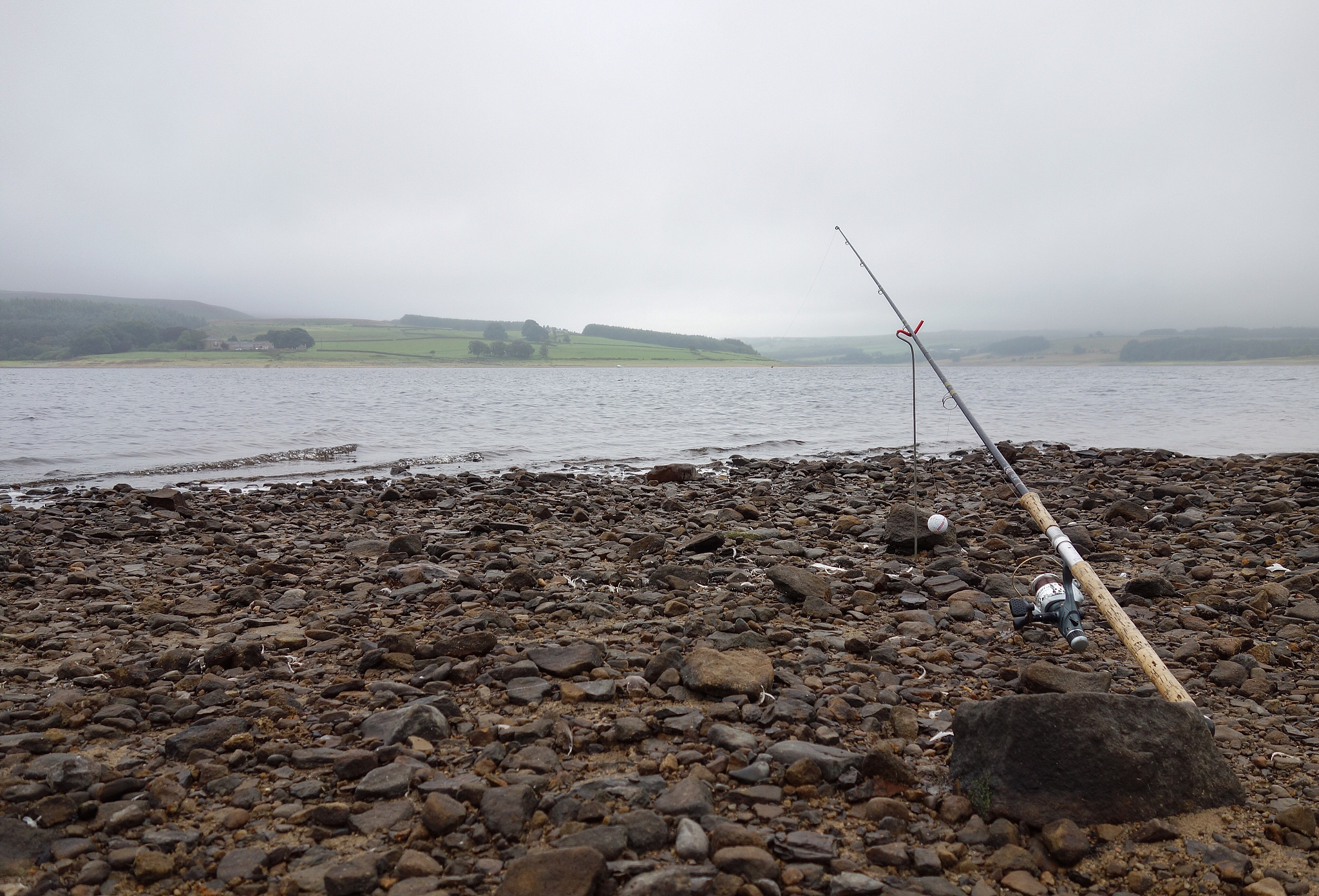 fishing rod on field by river against sky