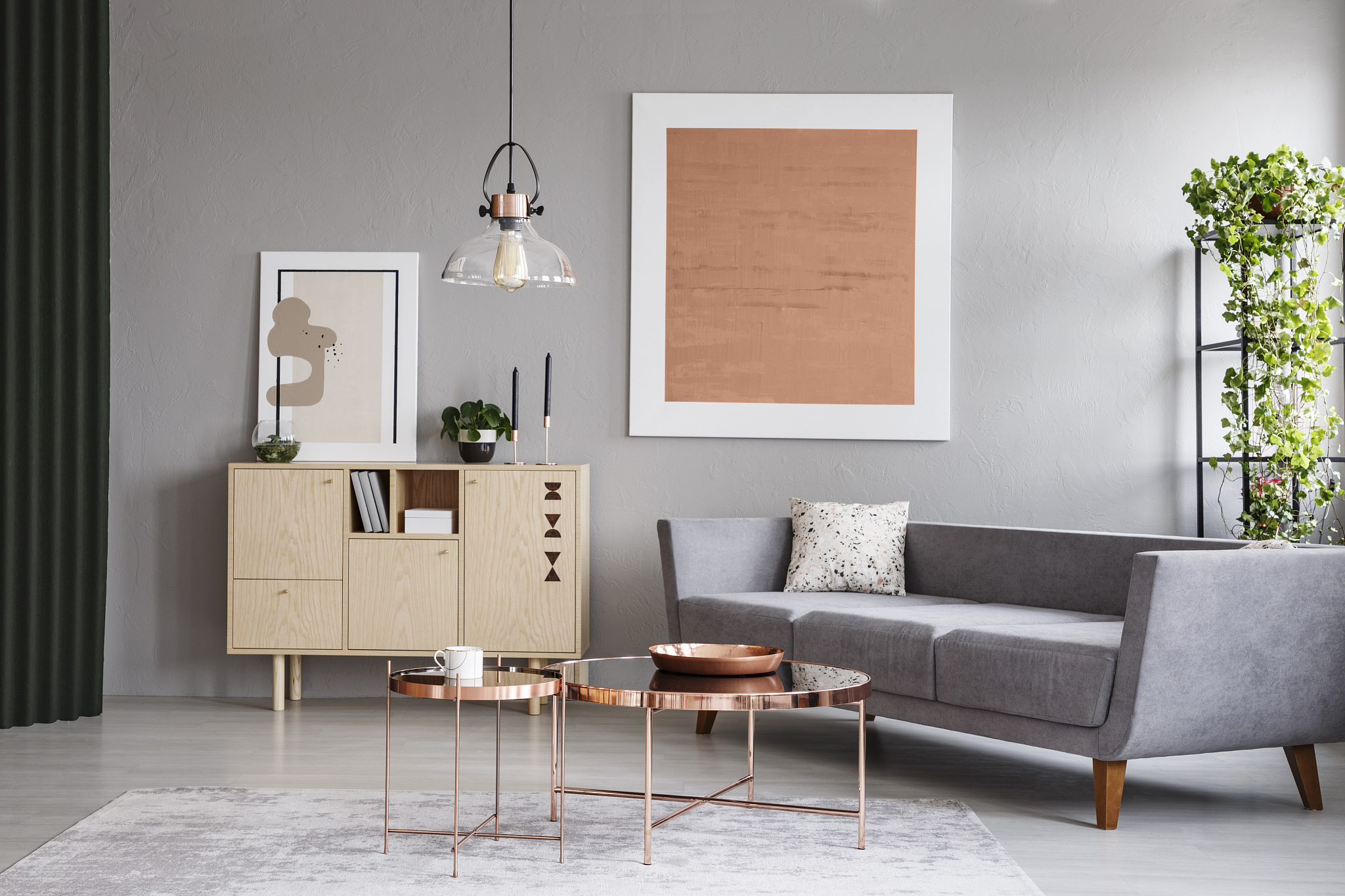 modern couch and copper tables in a grey living room interior wi