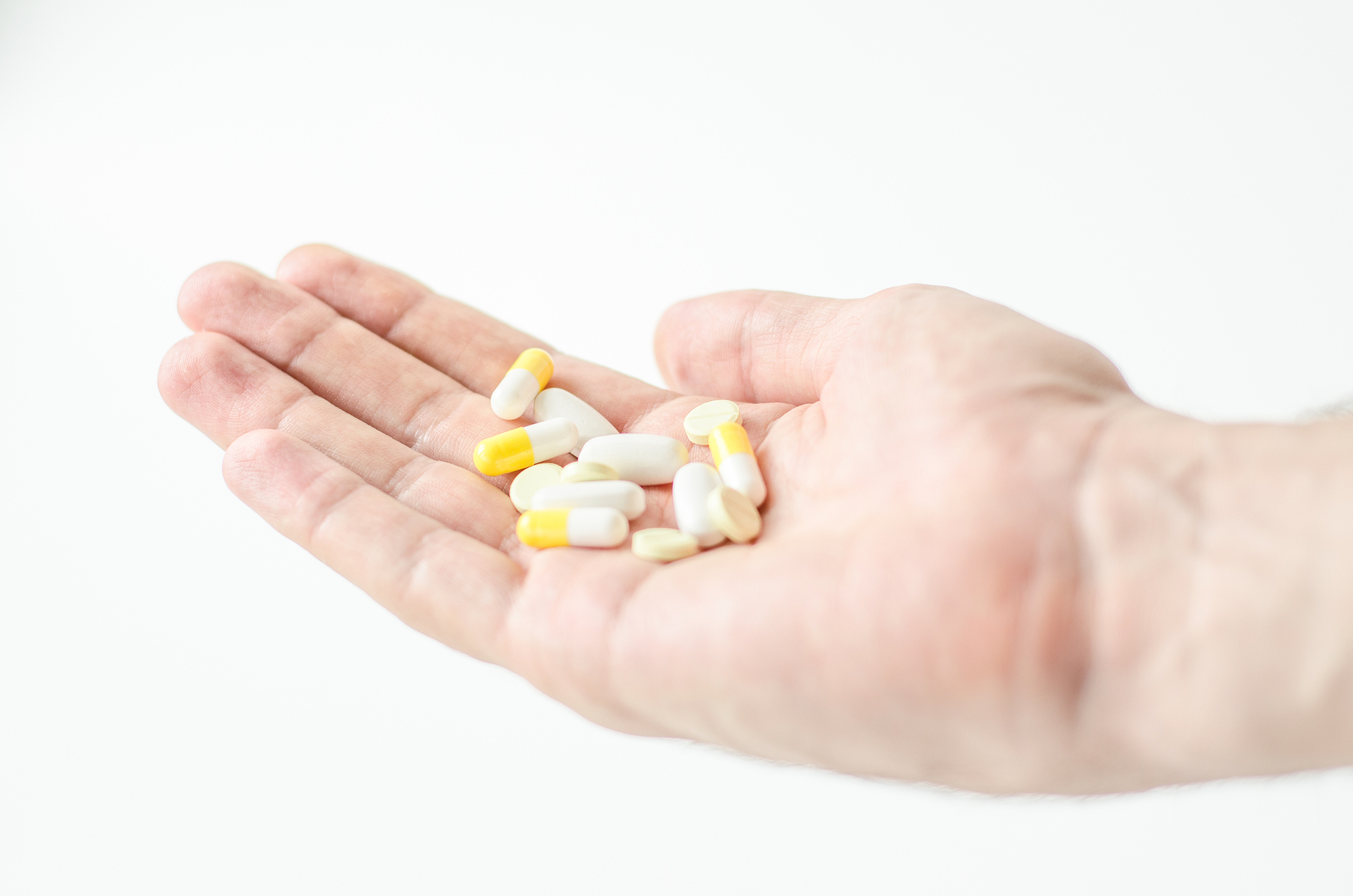 close up photo of one round pill in young male hand. man takes m
