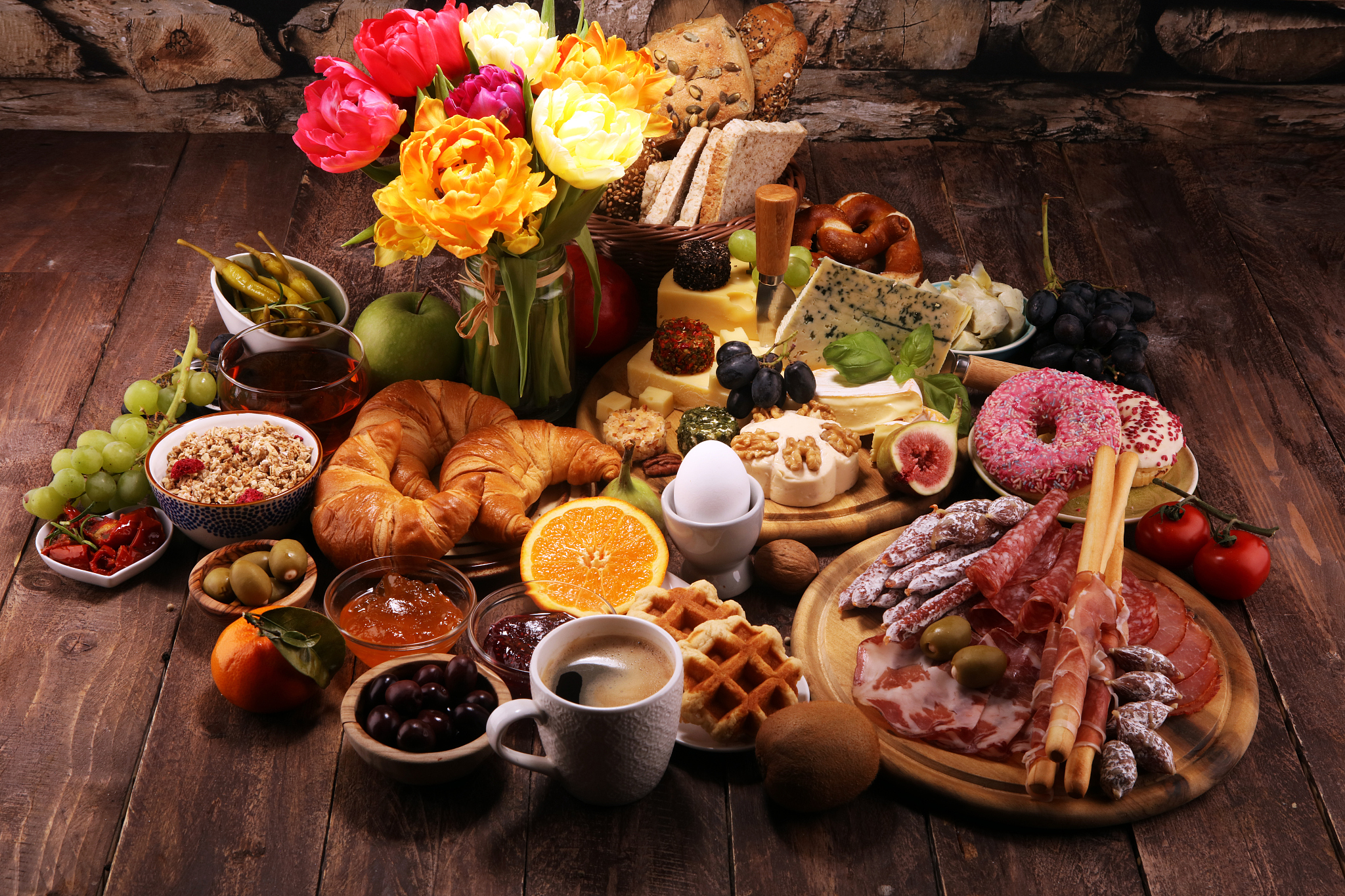 breakfast on table with bread buns, croissants, coffe and eggs