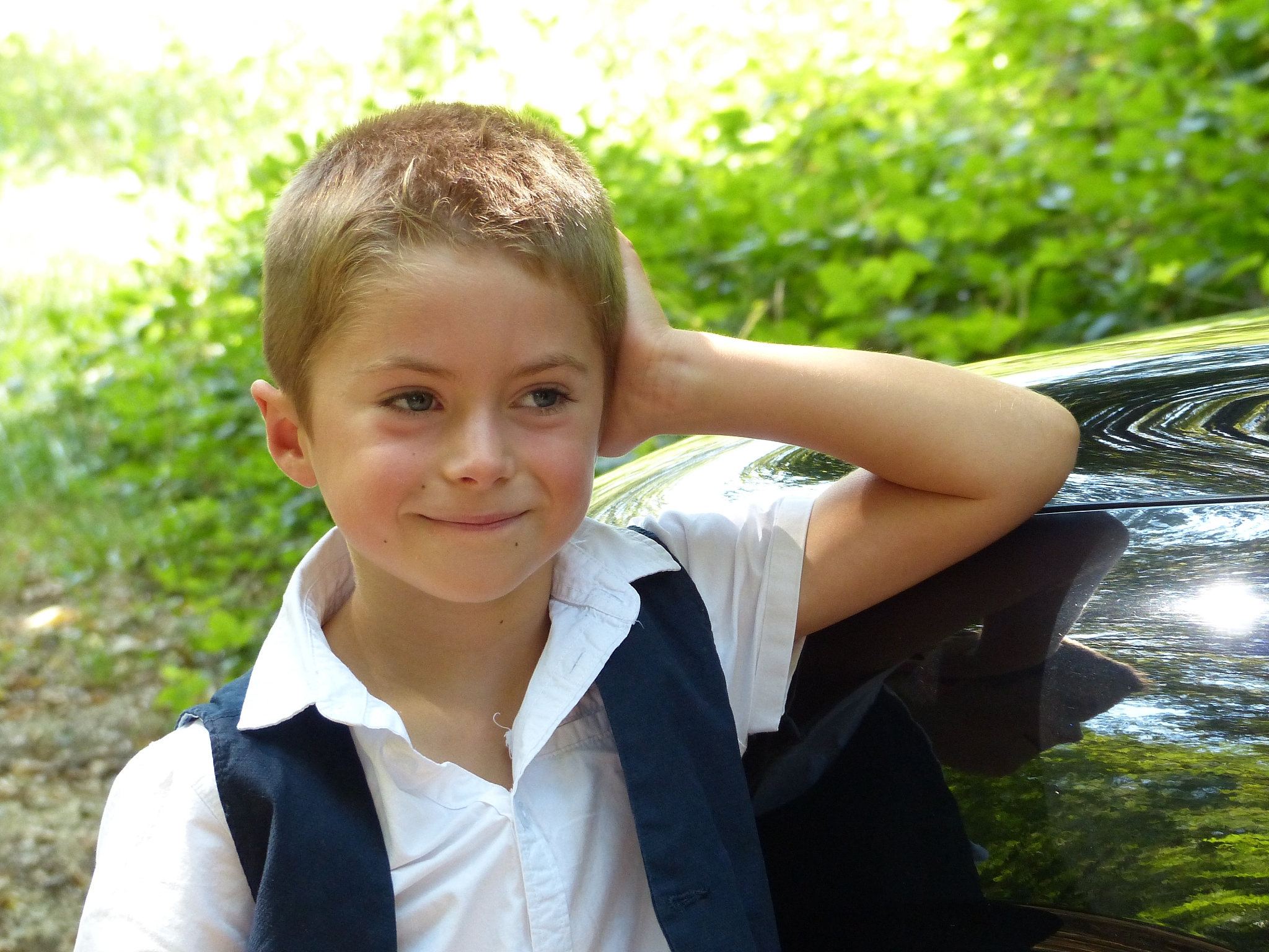 smiling and proud child leaning on a car