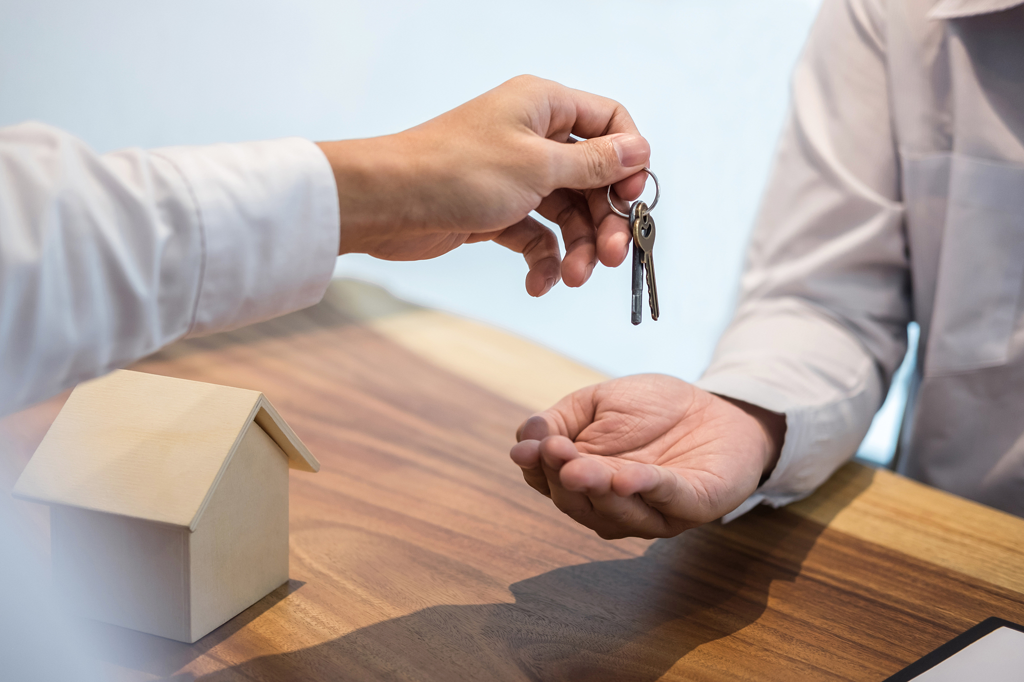 broker agent's hand holding house key in insurance, giving to bu