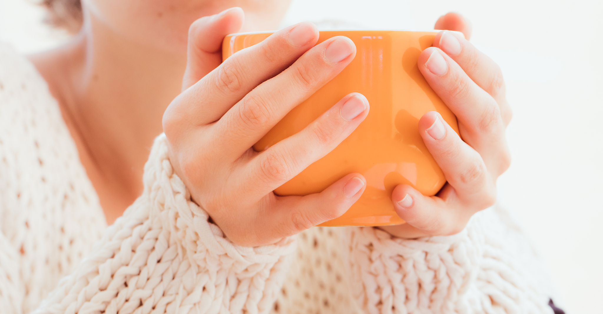 closeup of woman's hands holding orange jumbo mug
