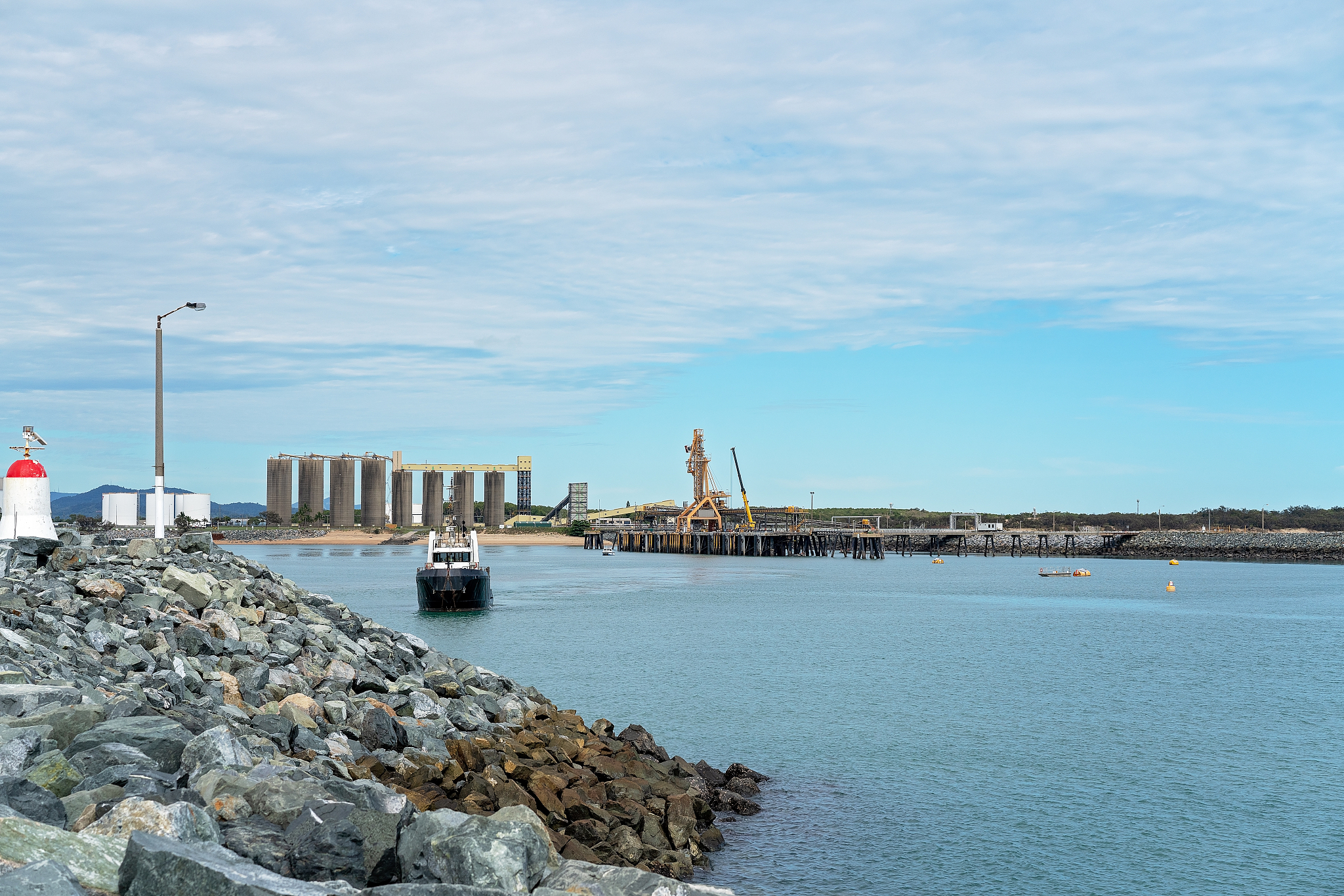 tug boat sailing towards a lighthouse at a wharf