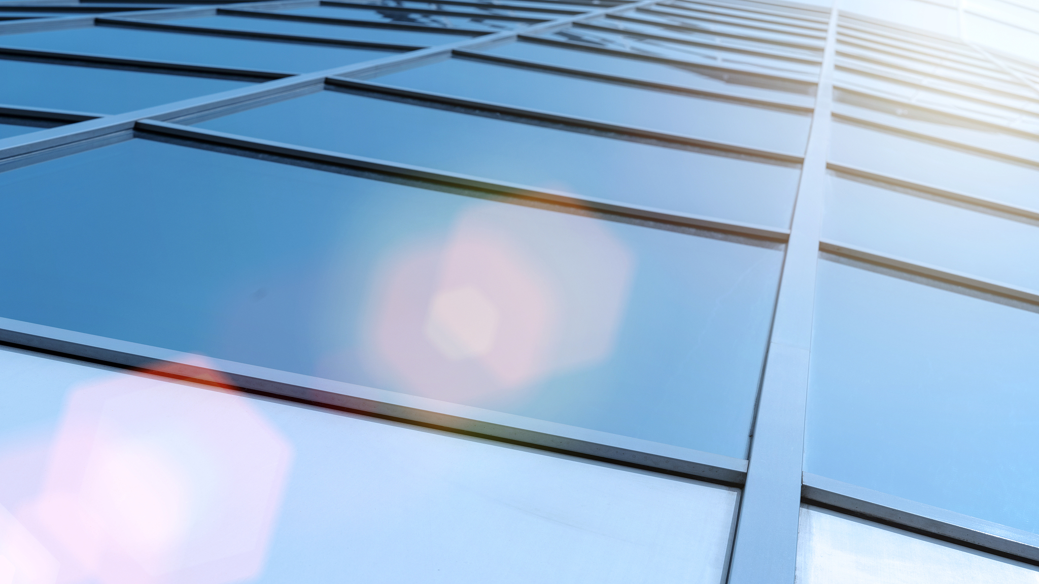 bright sunrays falling on modern glass wall with window with alu
