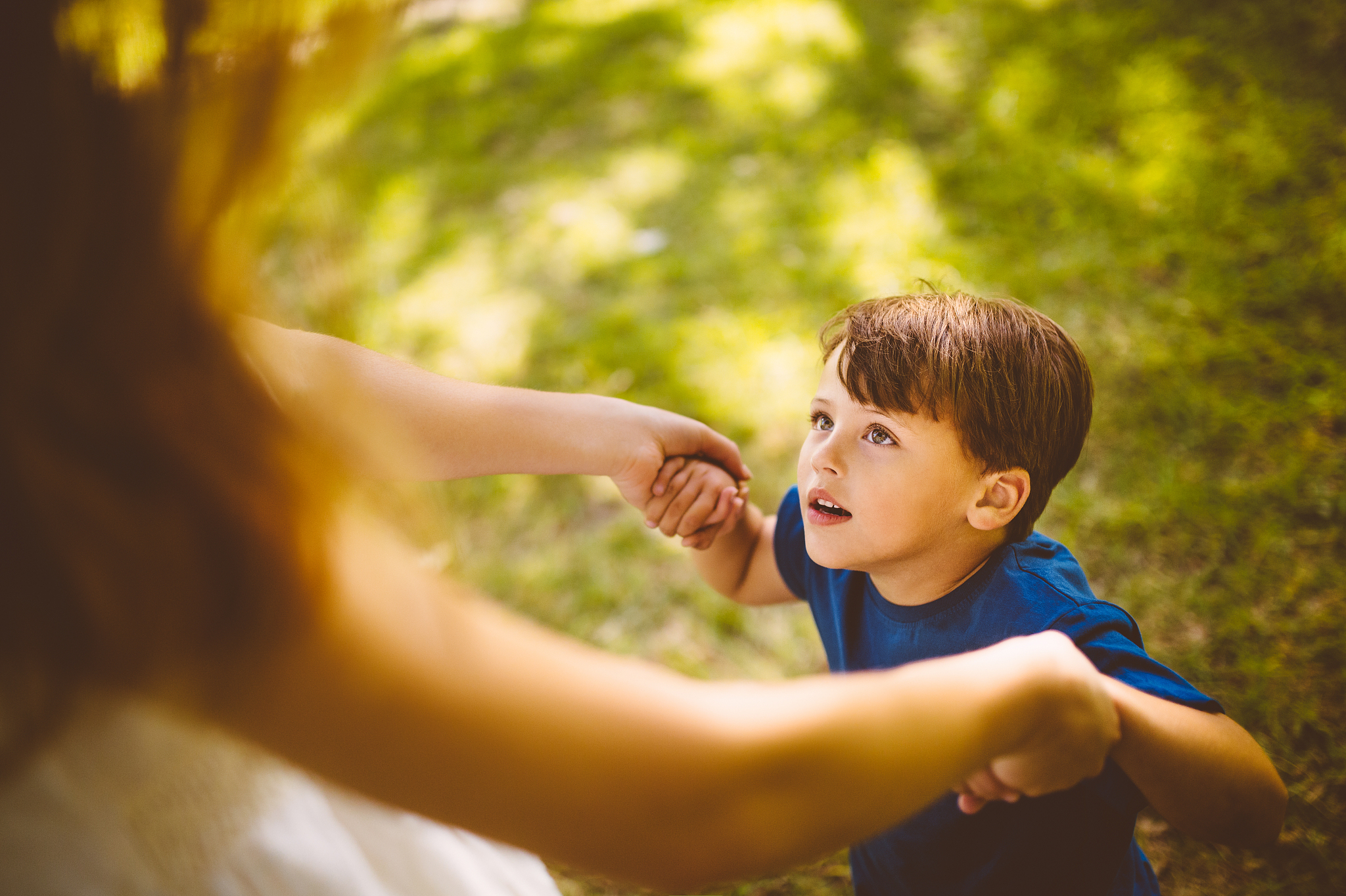 little boy playing with his mom outside on the grass