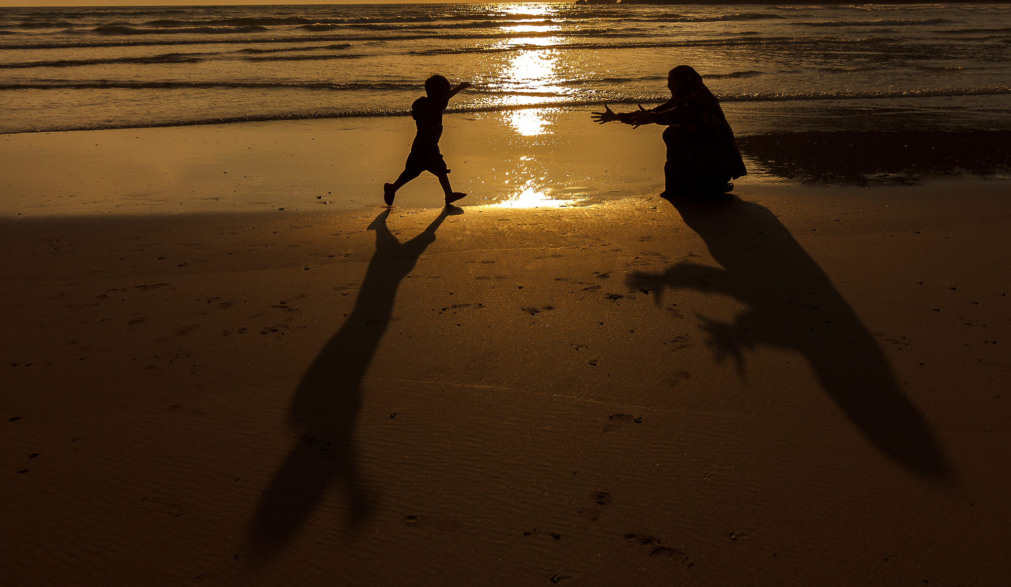 silhouette mother and son playing at beach