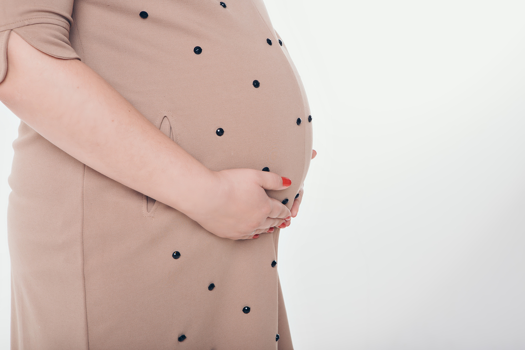 pregnant woman holding hands on belly on a white background
