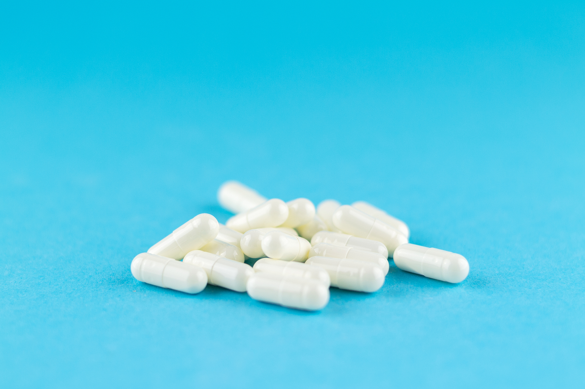 close up white capsules on blue background with copy space. focu