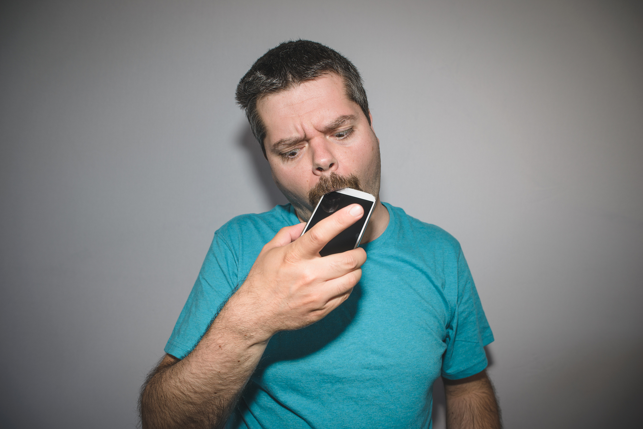 man biting and chewing on his smart phone