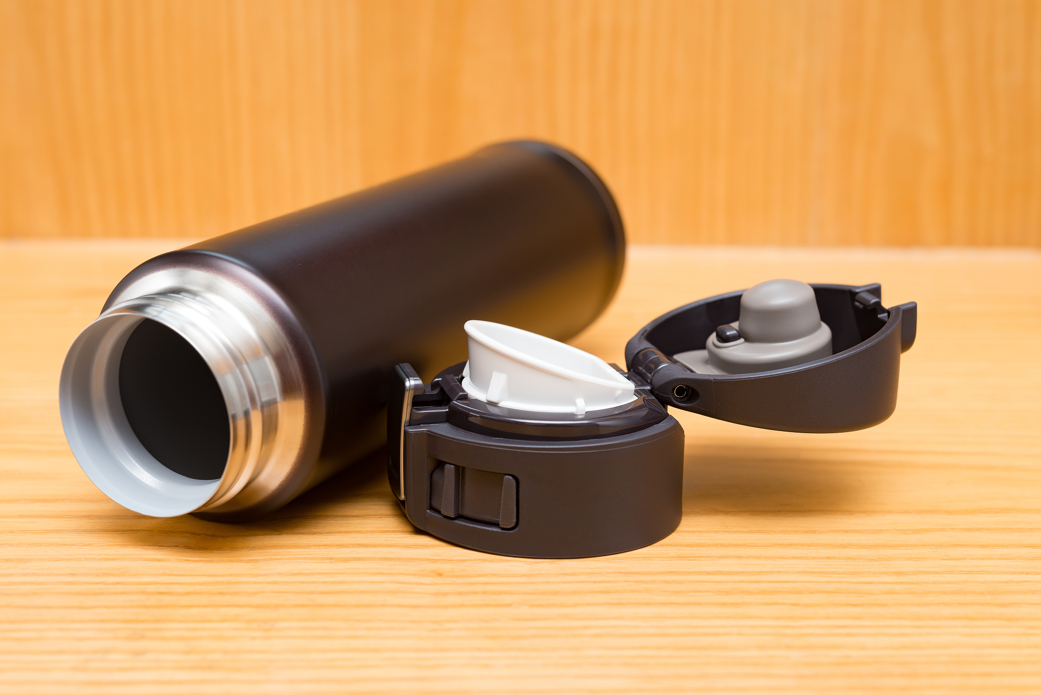opened burgundy vacuum tumbler with safety lock on wooden table