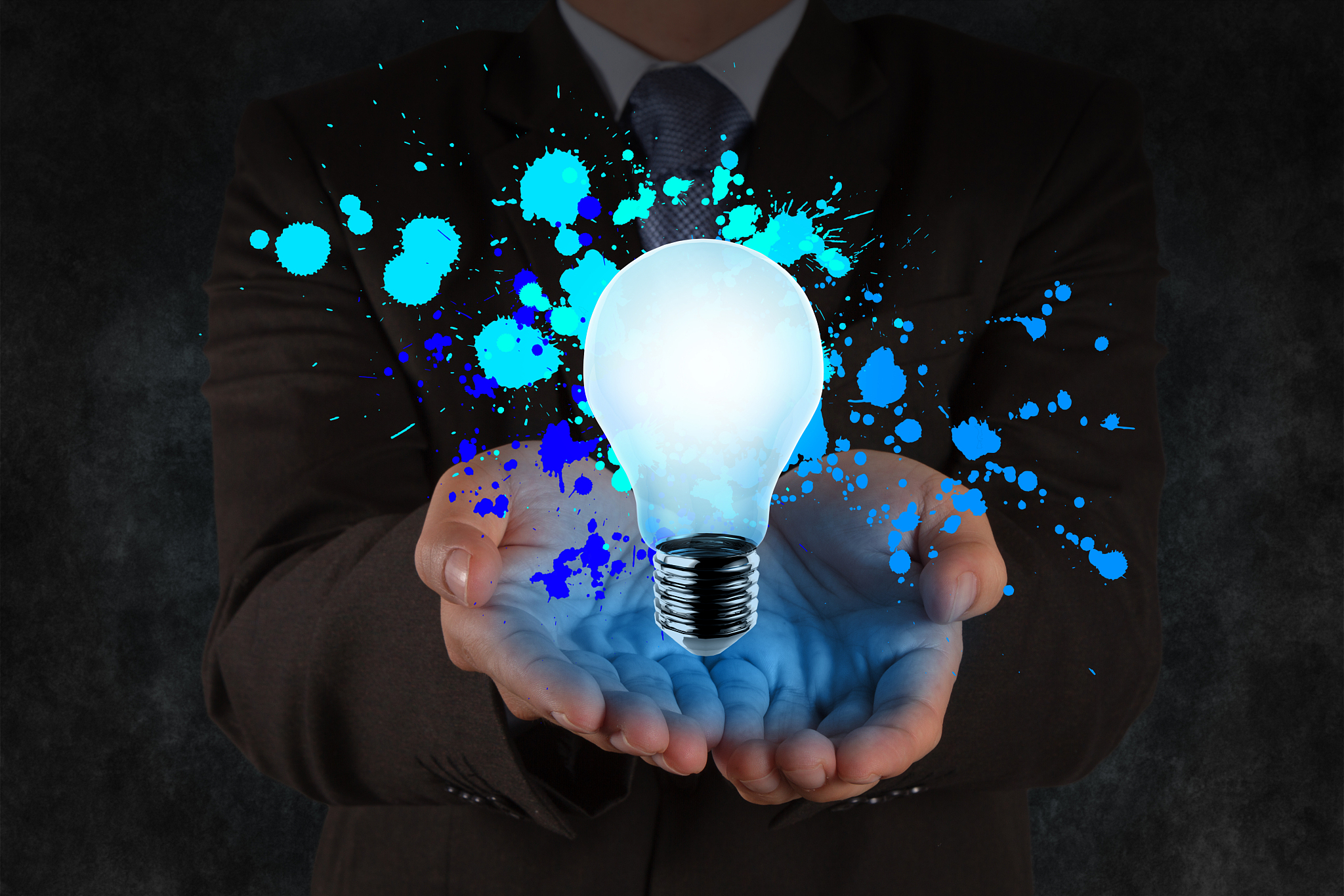 businessman hand shows light bulb and splash colors