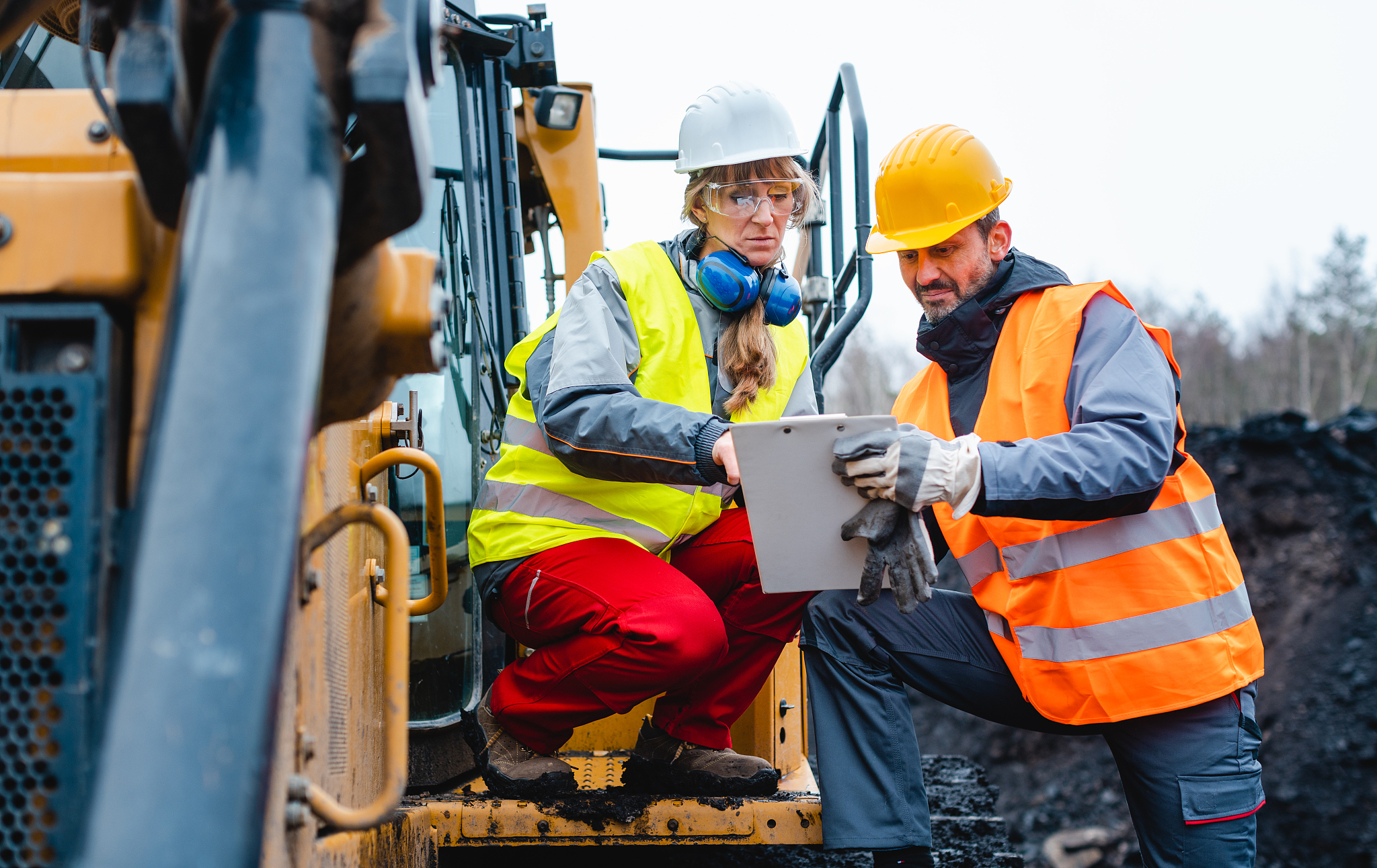 woman and man worker in quarry on excavation machine