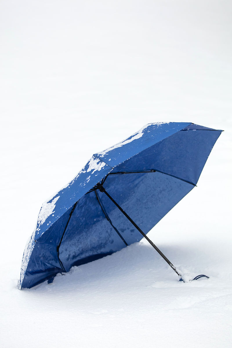 在寒冷的雪天丢弃的蓝色雨伞.