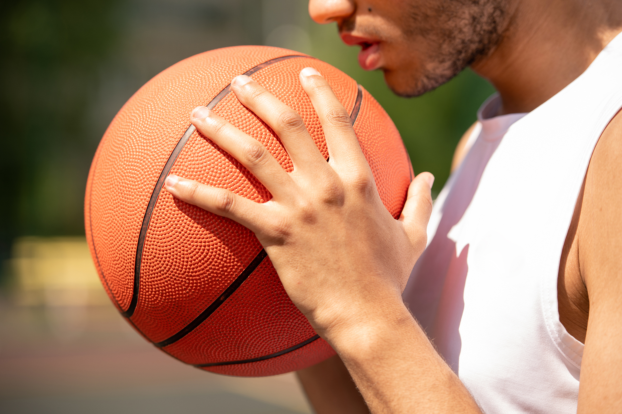 young contemporary male basketball player holding ball by his fa