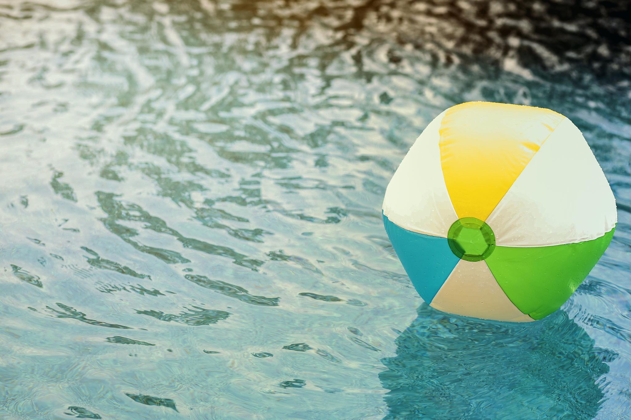 beach ball floating in refreshing swimming pool water.