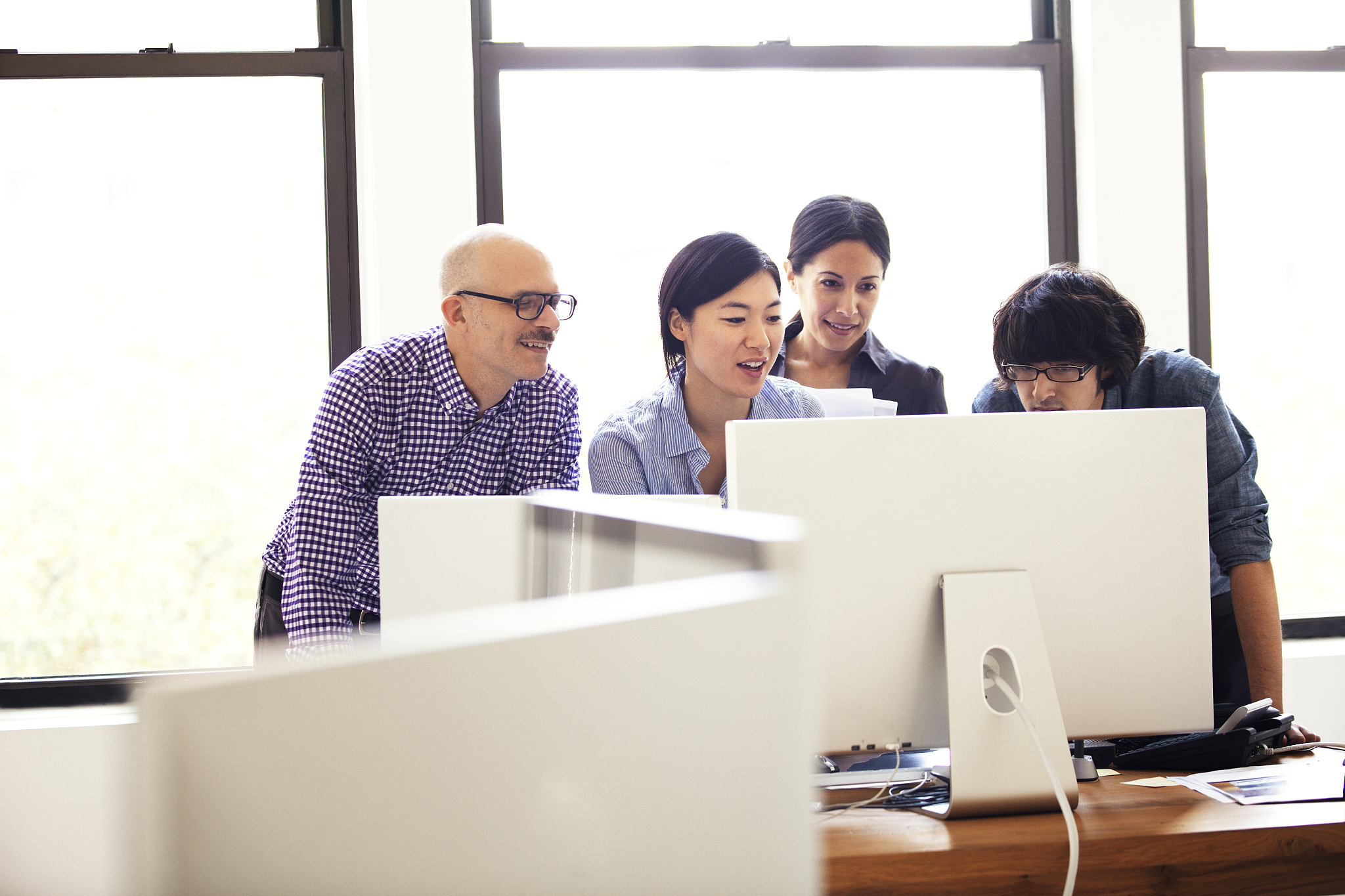 business people looking at computer while standing in office