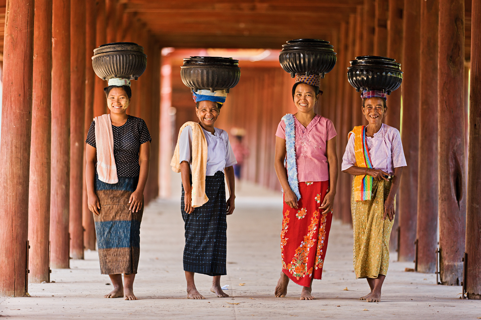 burmese women carrying bowls of rice to the monastery