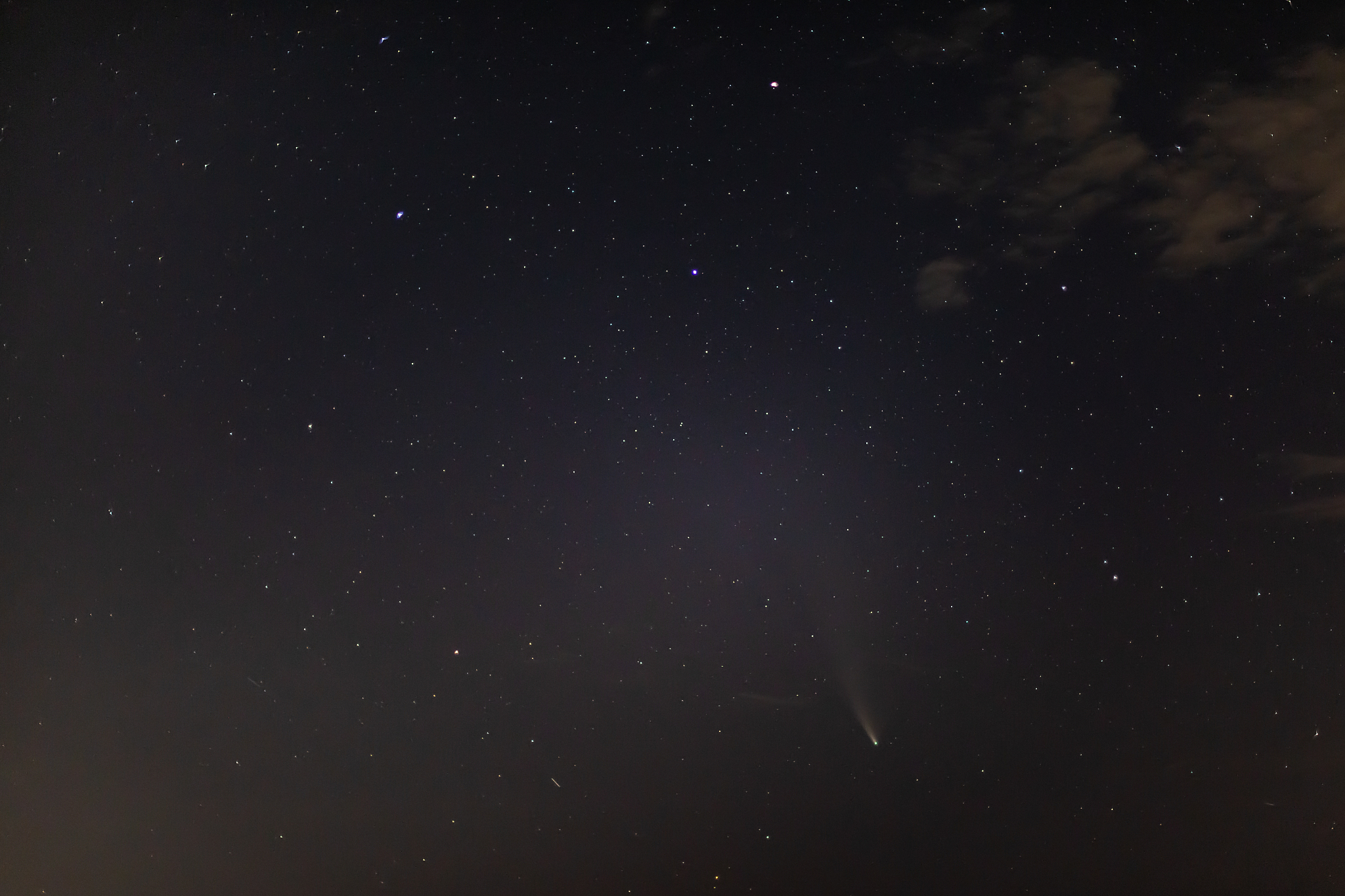 comet neowise on a dark starry sky with clouds next to the ursa 