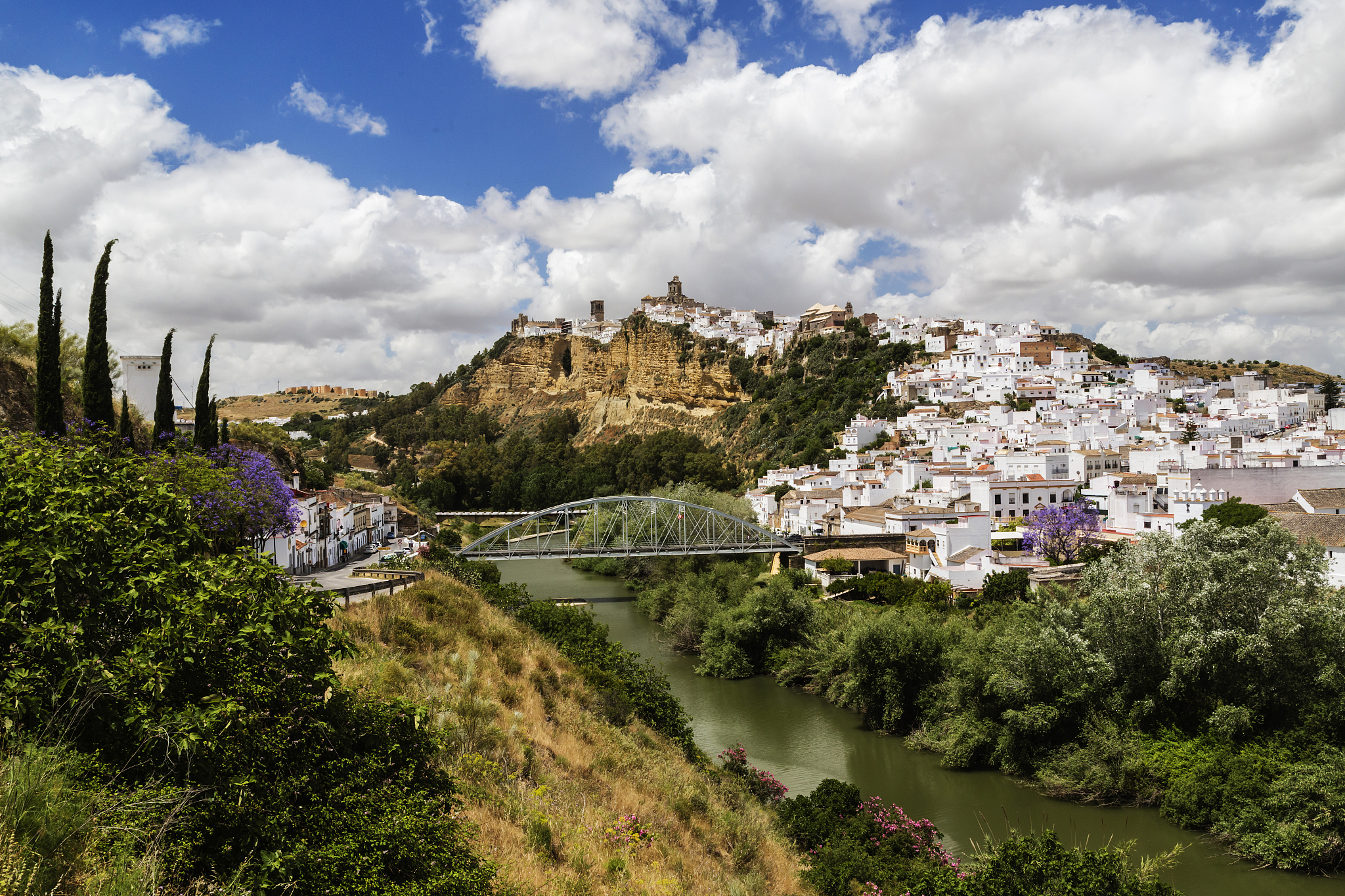 village on hillside near bridge and river, arcos de la frontera,