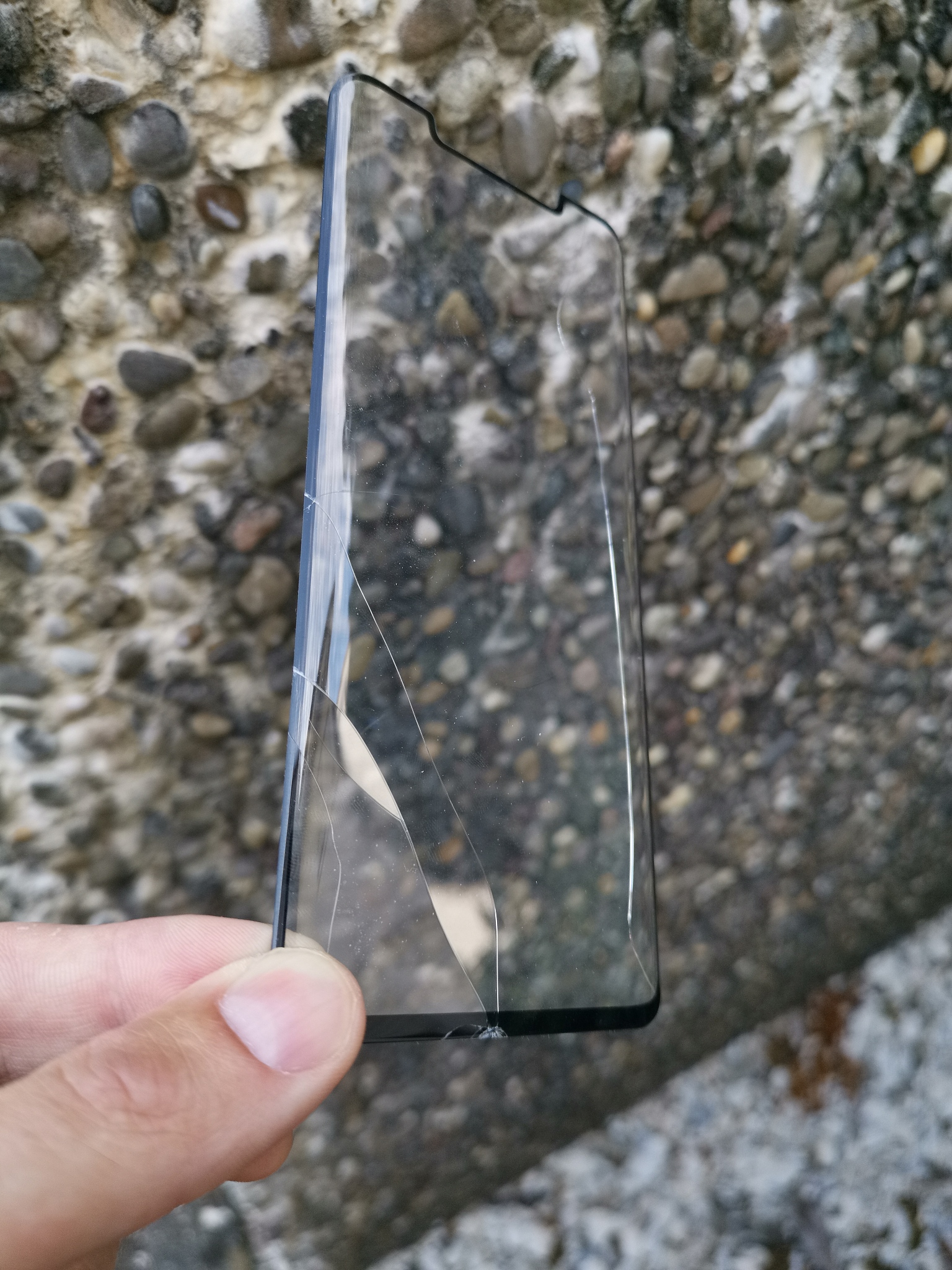 display of damaged smartphone glass protector in front of stone 