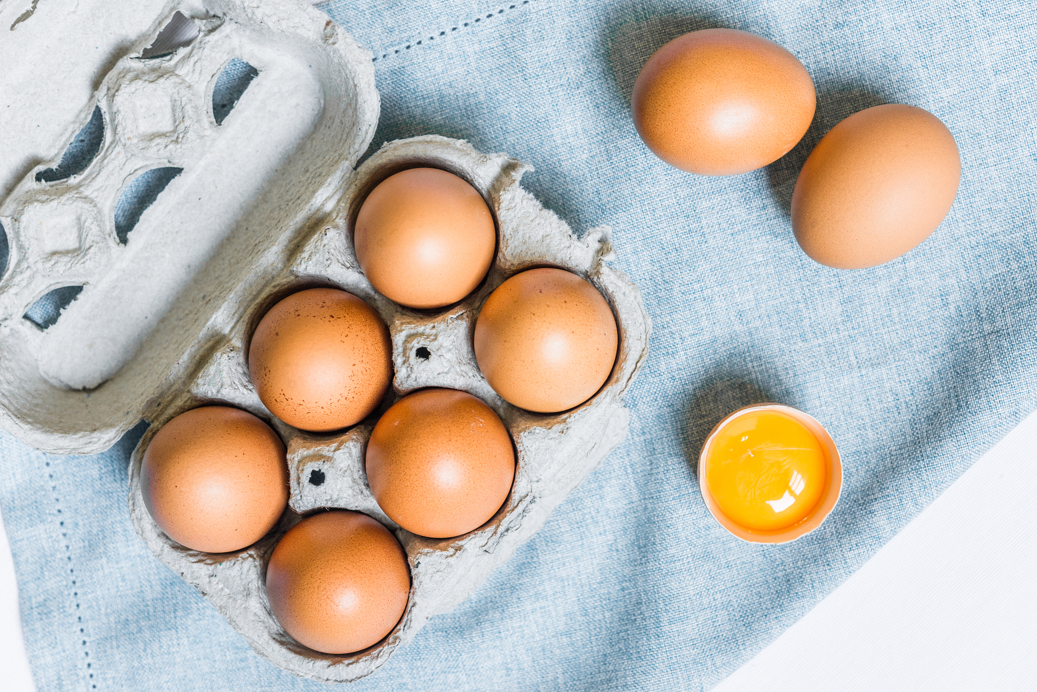 fresh chicken eggs against white and blue background