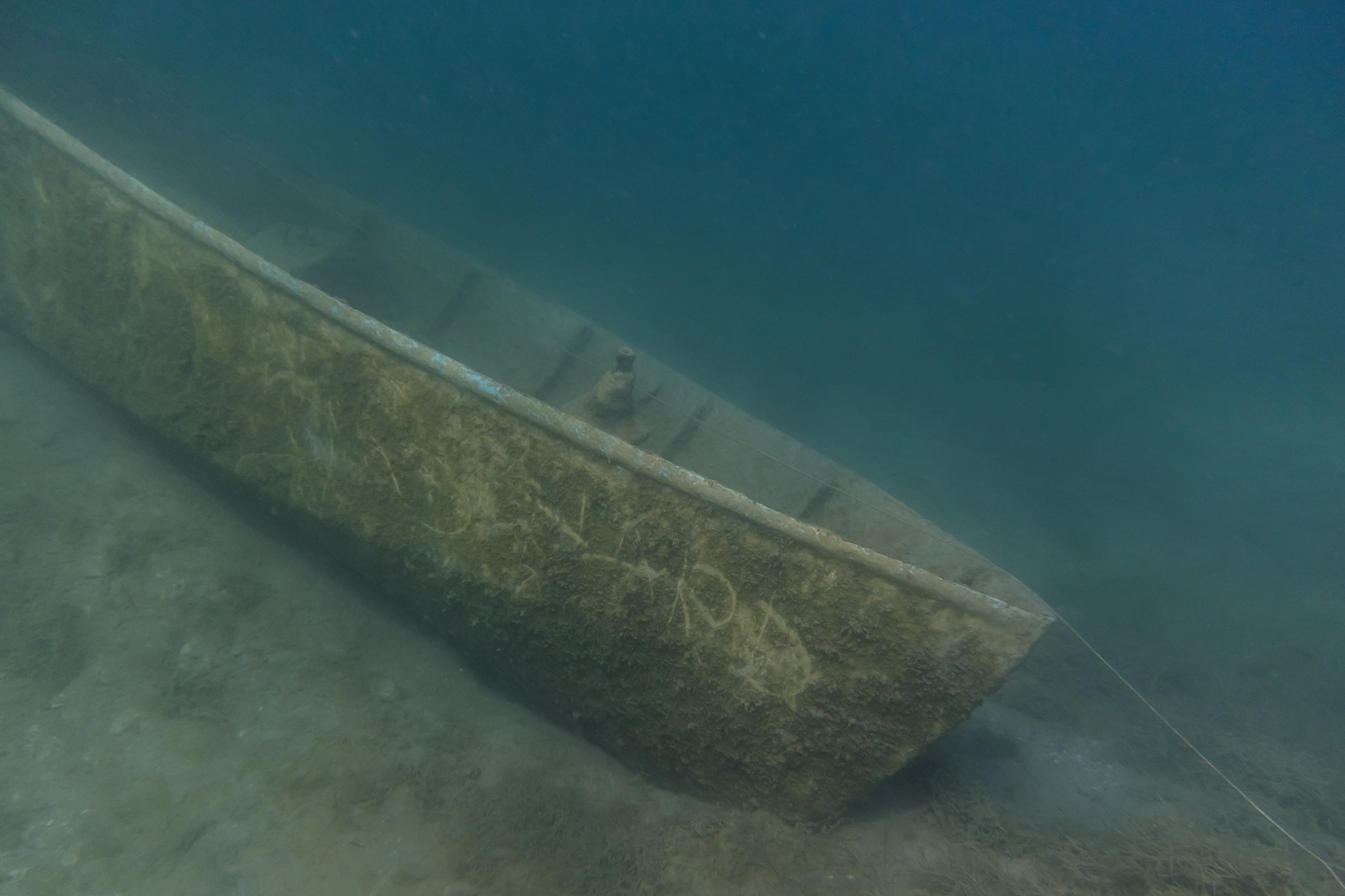 boat at the bottom of a lake with blue water