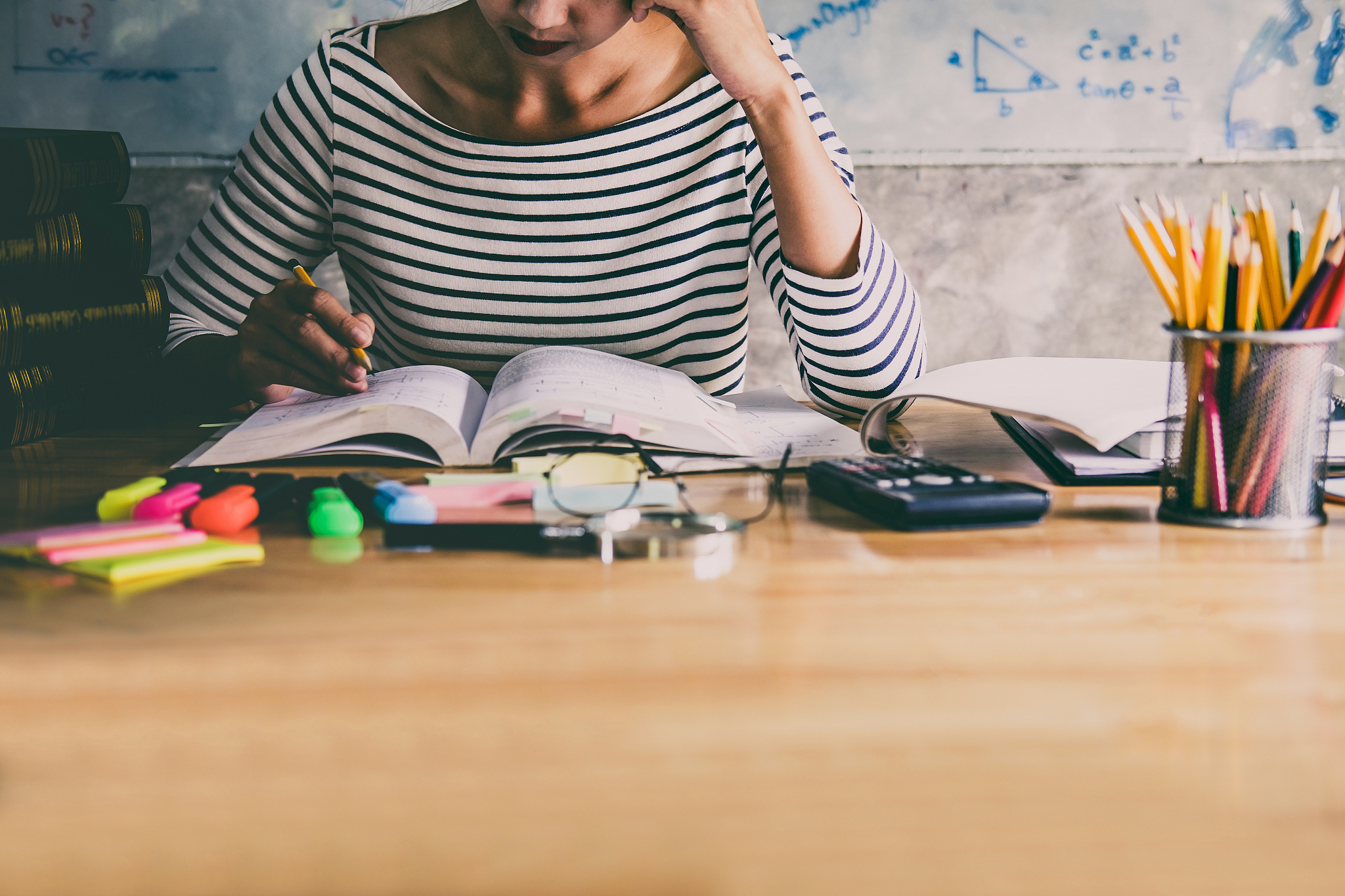 young student sitting at desk in home studying and reading, doin