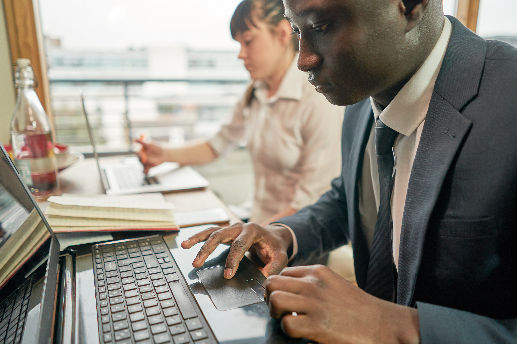 two people working together on a hot desk with computers.