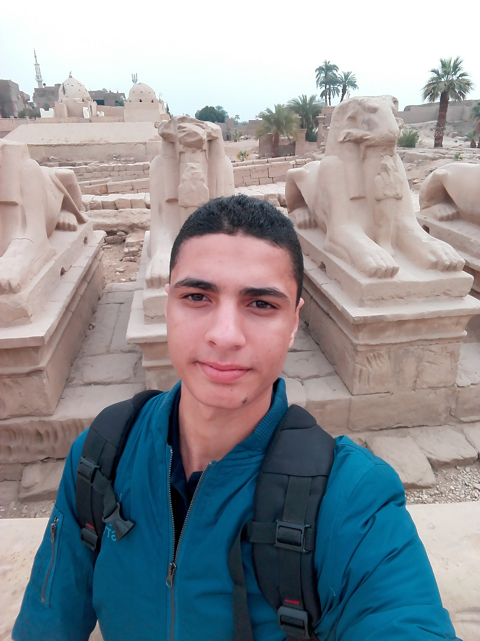 portrait of young man with backpack standing against old ruin