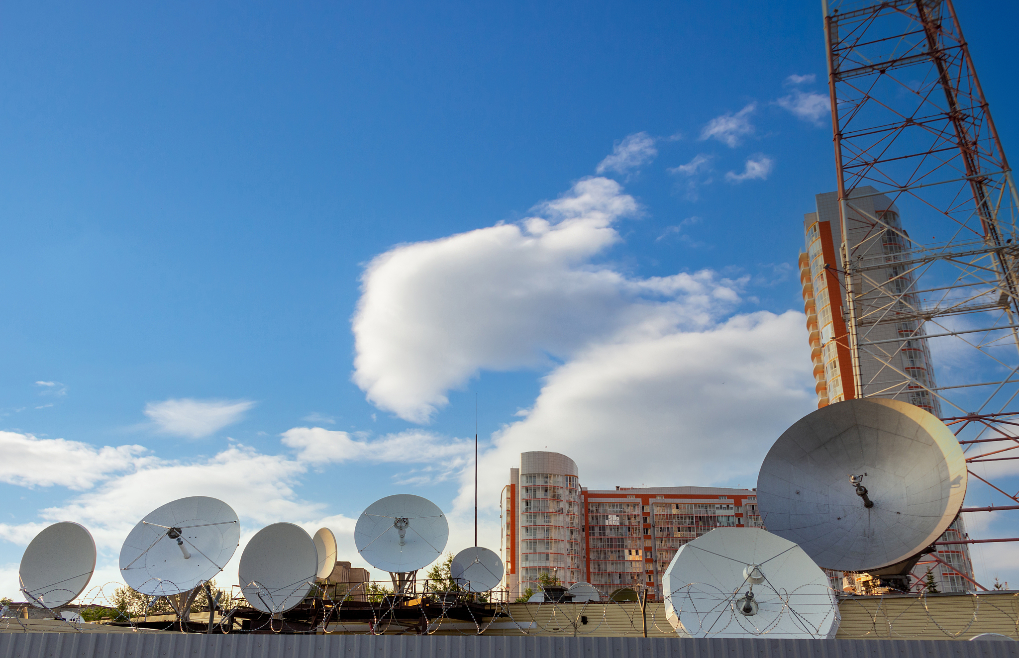 many parabolic antennas against sky in city. satellite communica