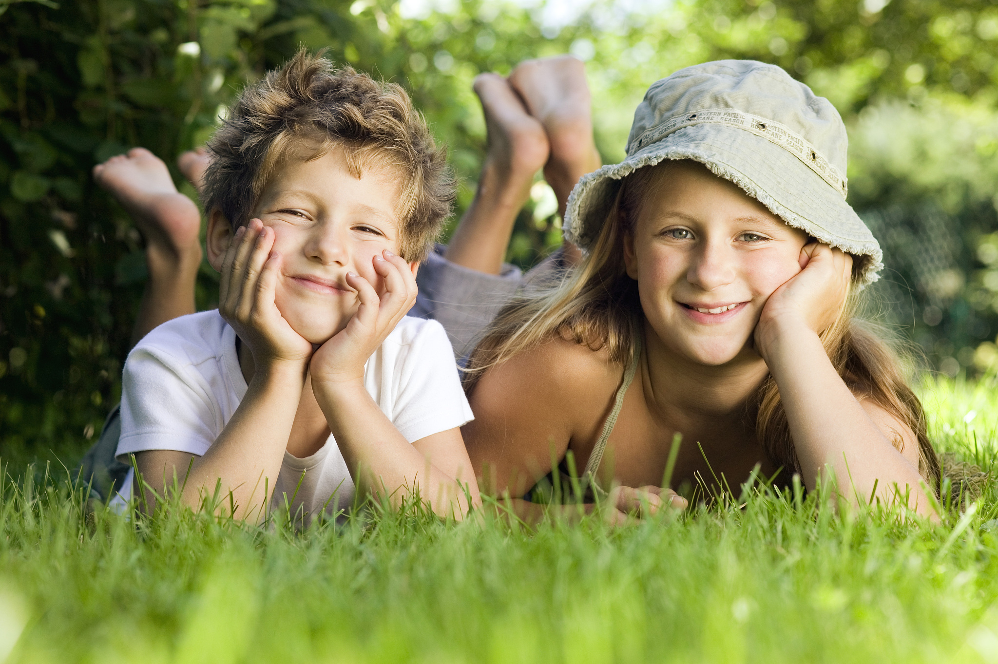 boy and girl (6-9) lying on grass, portrait