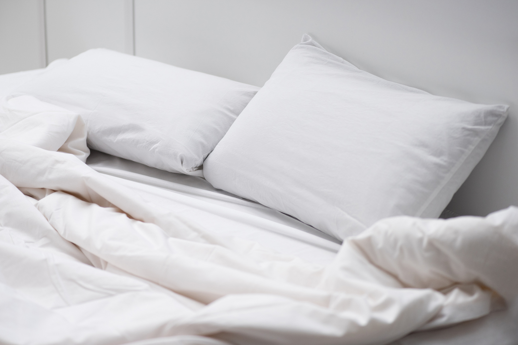 empty bed with white pillows and blanket