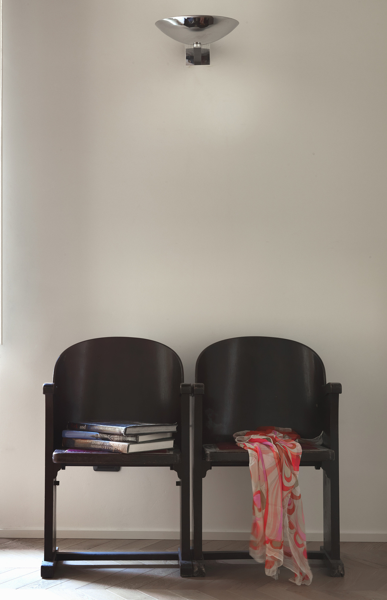 two old, black cinema seats against white wall