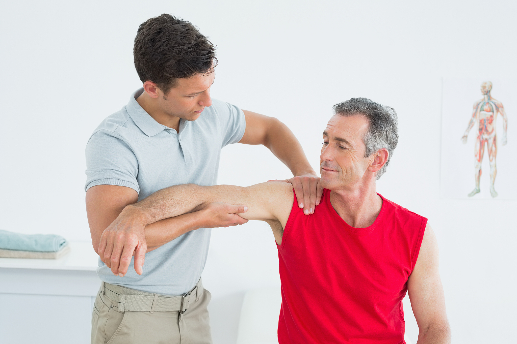 physiotherapist massaging mature mans arm