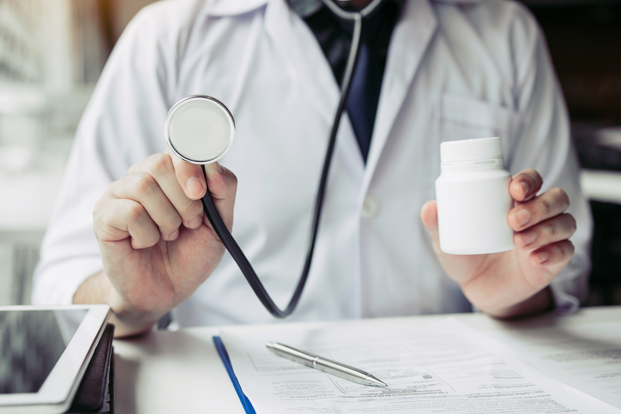 the doctor is carrying a stethoscope and a medicine jar on his h