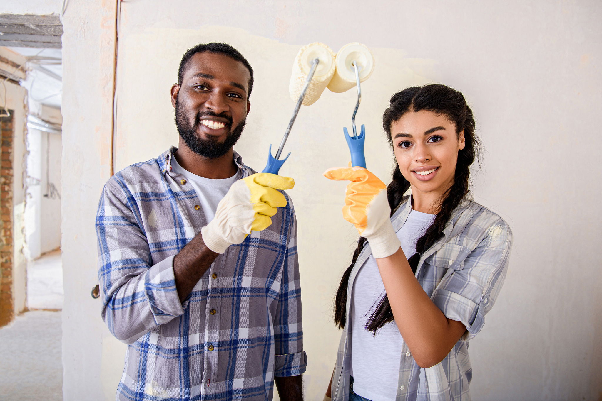 cheerful african american couple holding paint rollers and looki