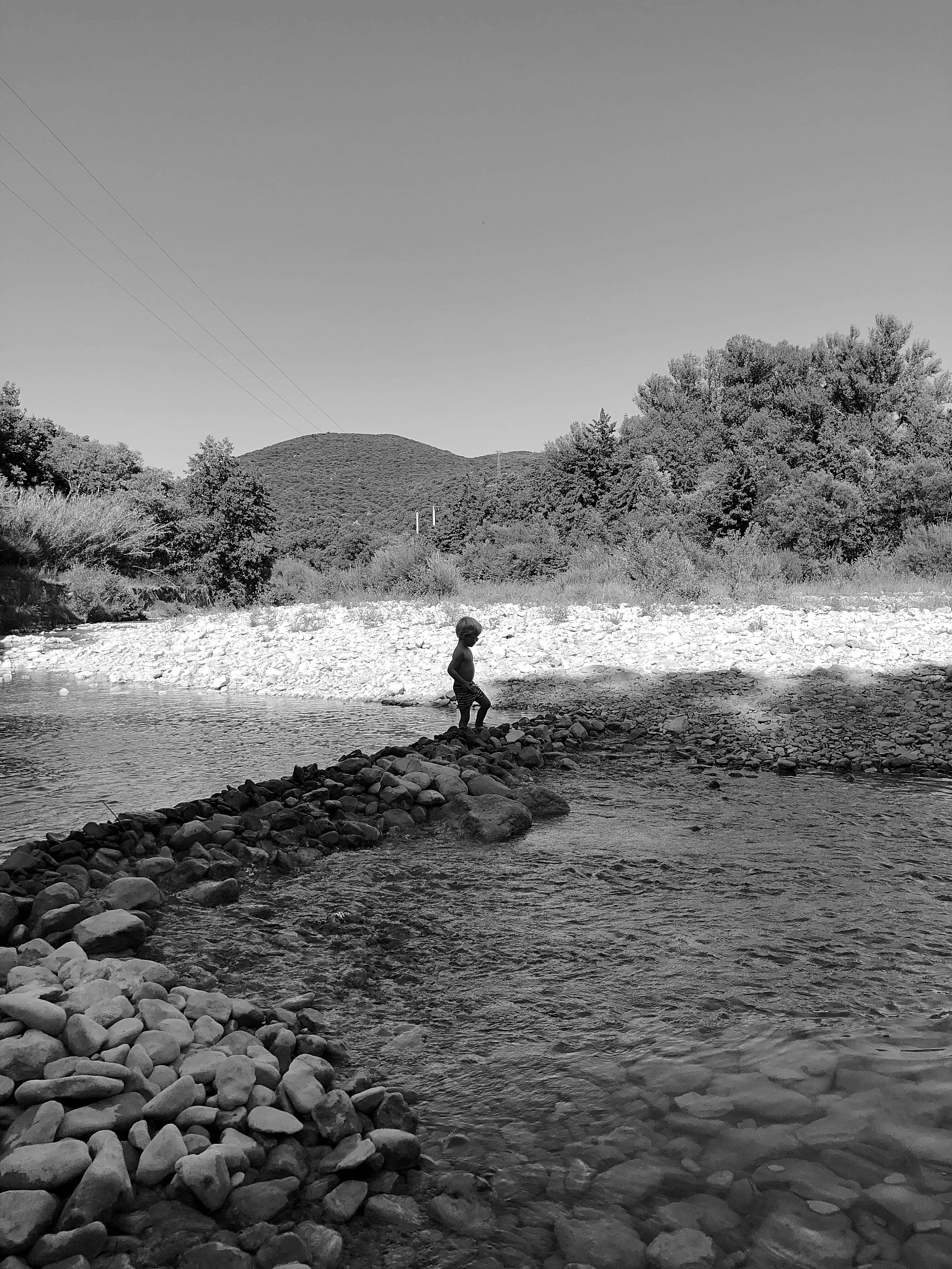 man at riverbank against clear sky