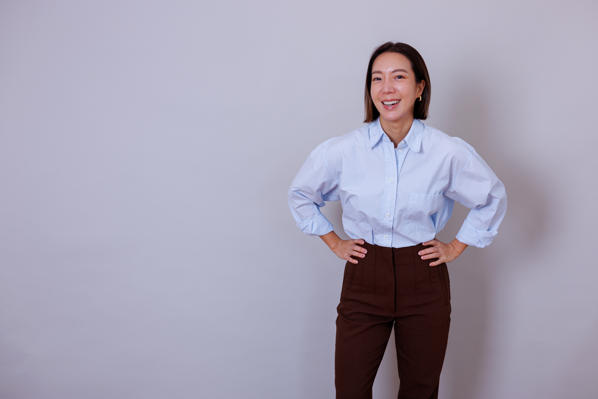 一位自信的女商人在叉腰站立时微笑,展现出成功和赋权