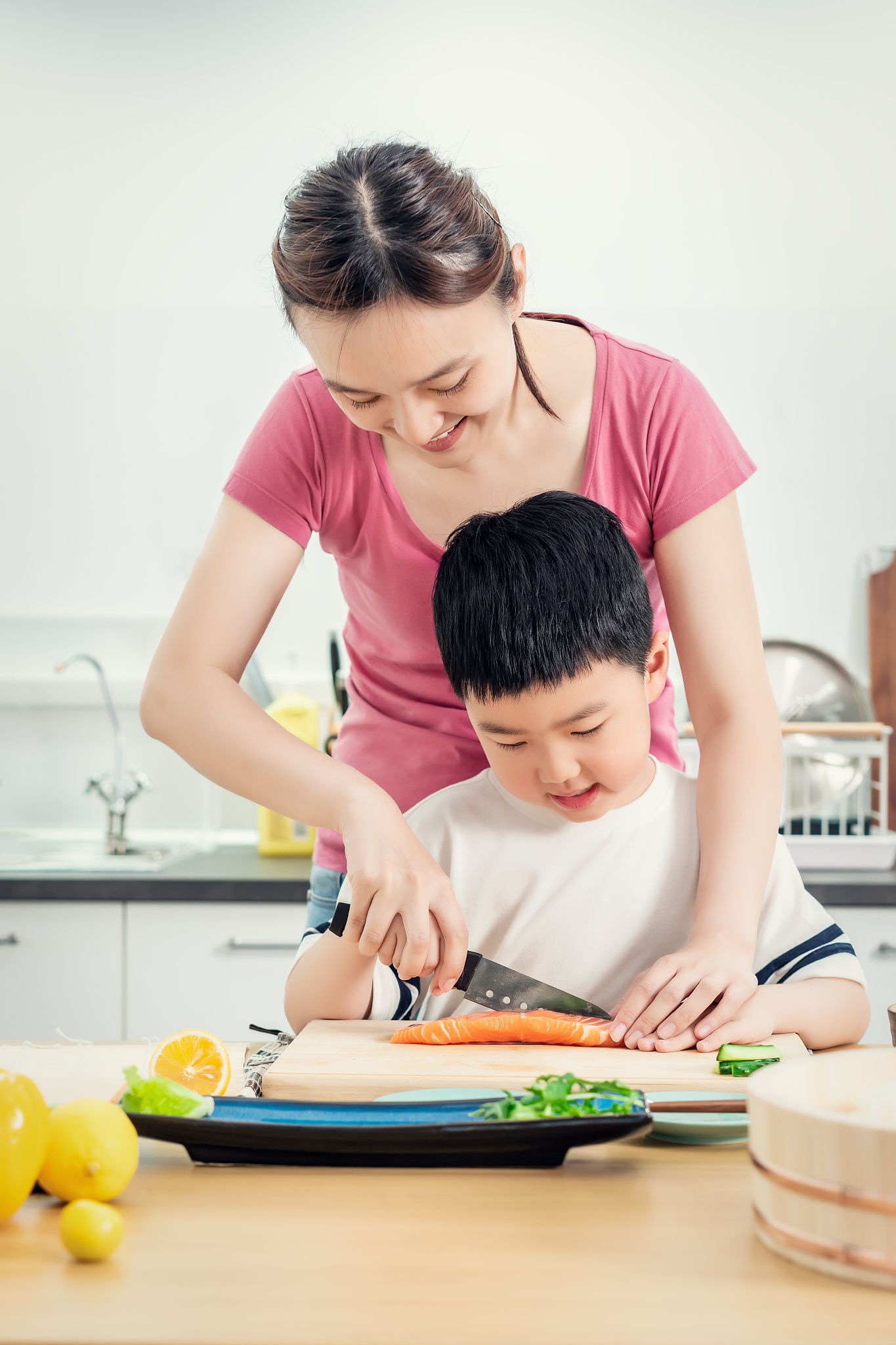 senior woman chopping salmon with her son in kitchen