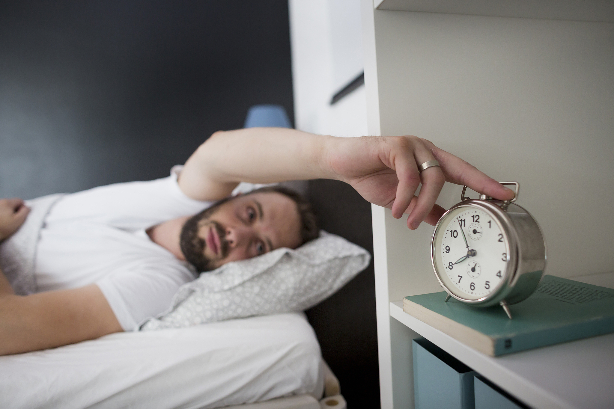 man waking up in his bedroom and stopping alarm clock. it's morn