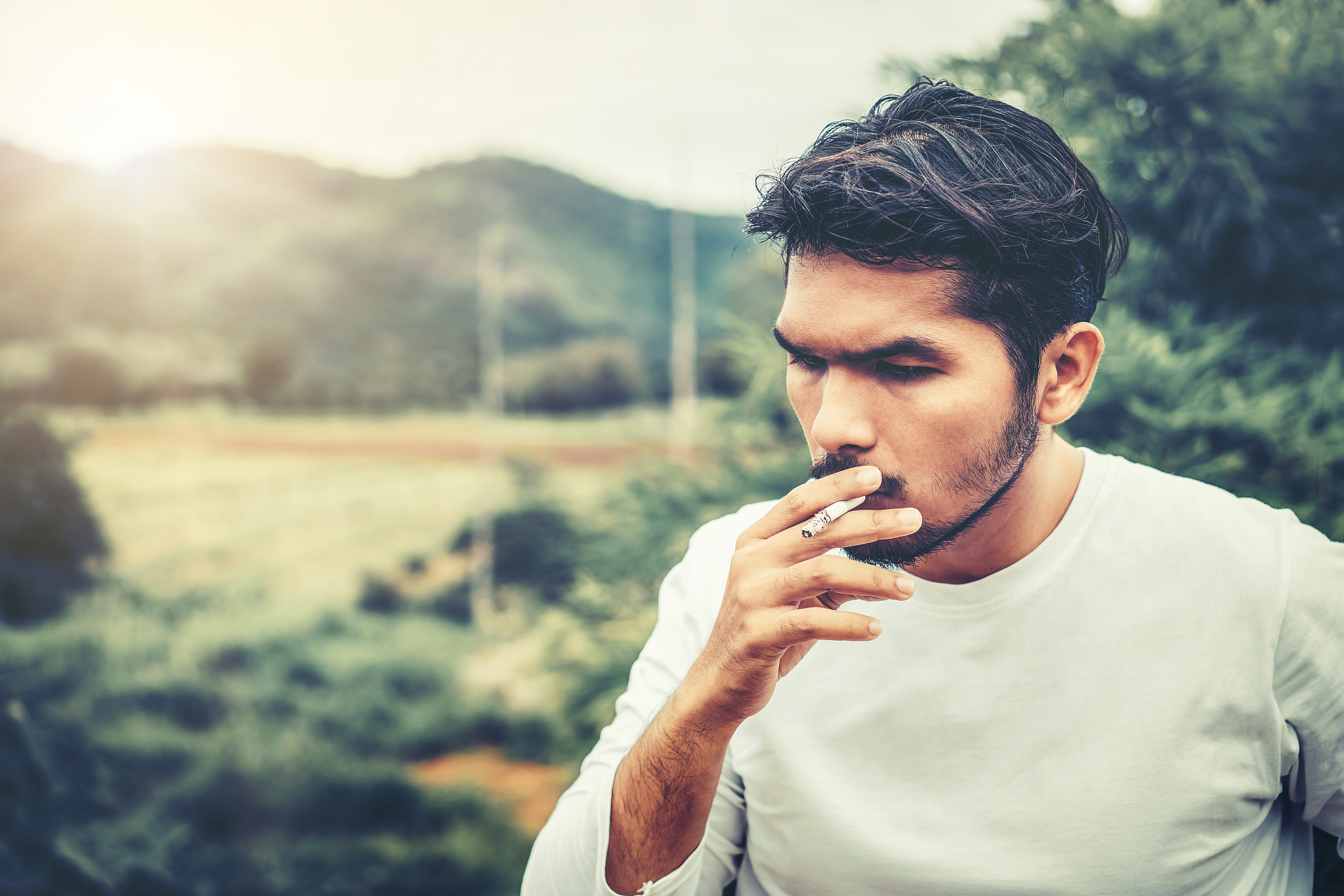 young man smoking cigarette in the outdoors.