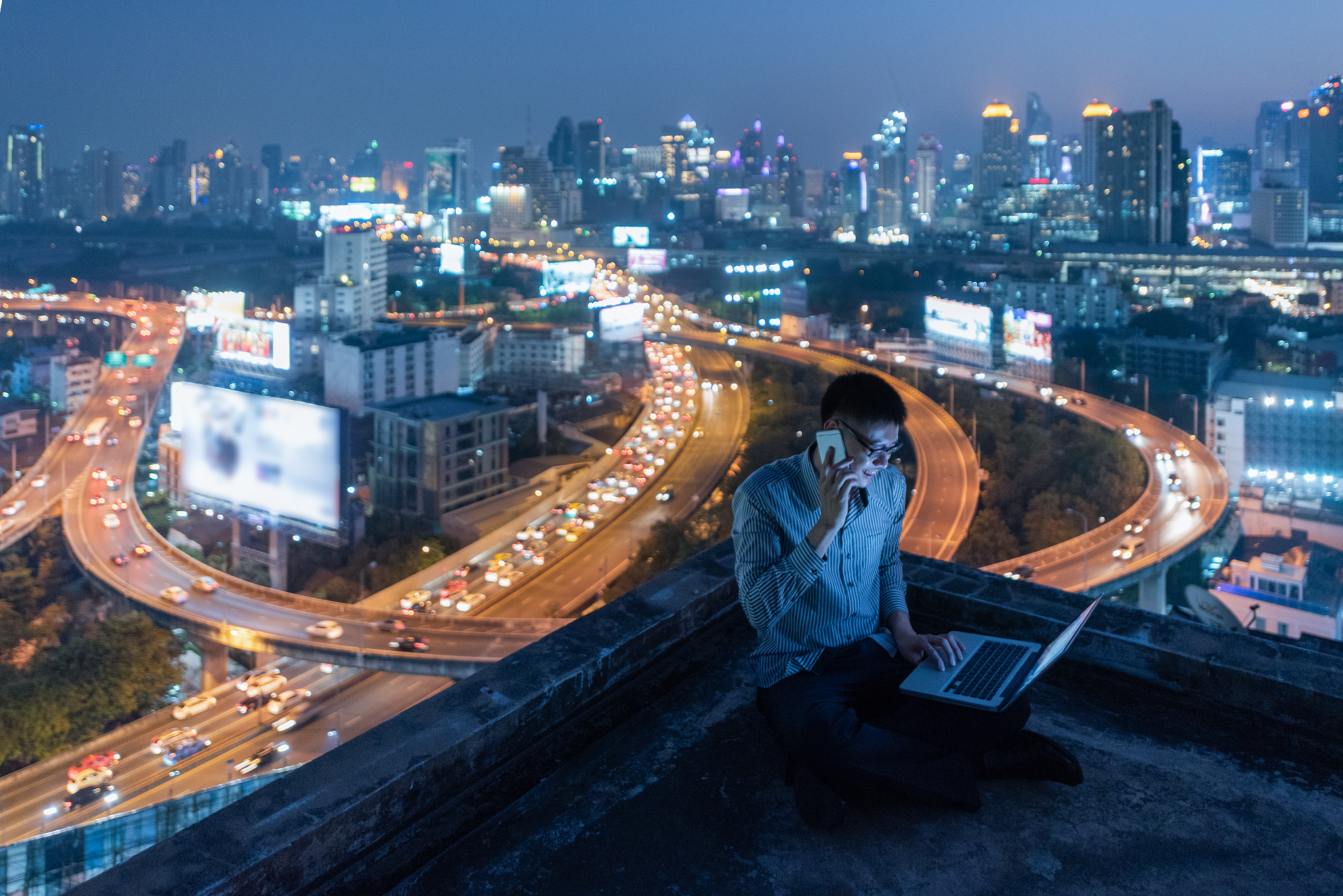 business man work late talking phone on rooftop at night