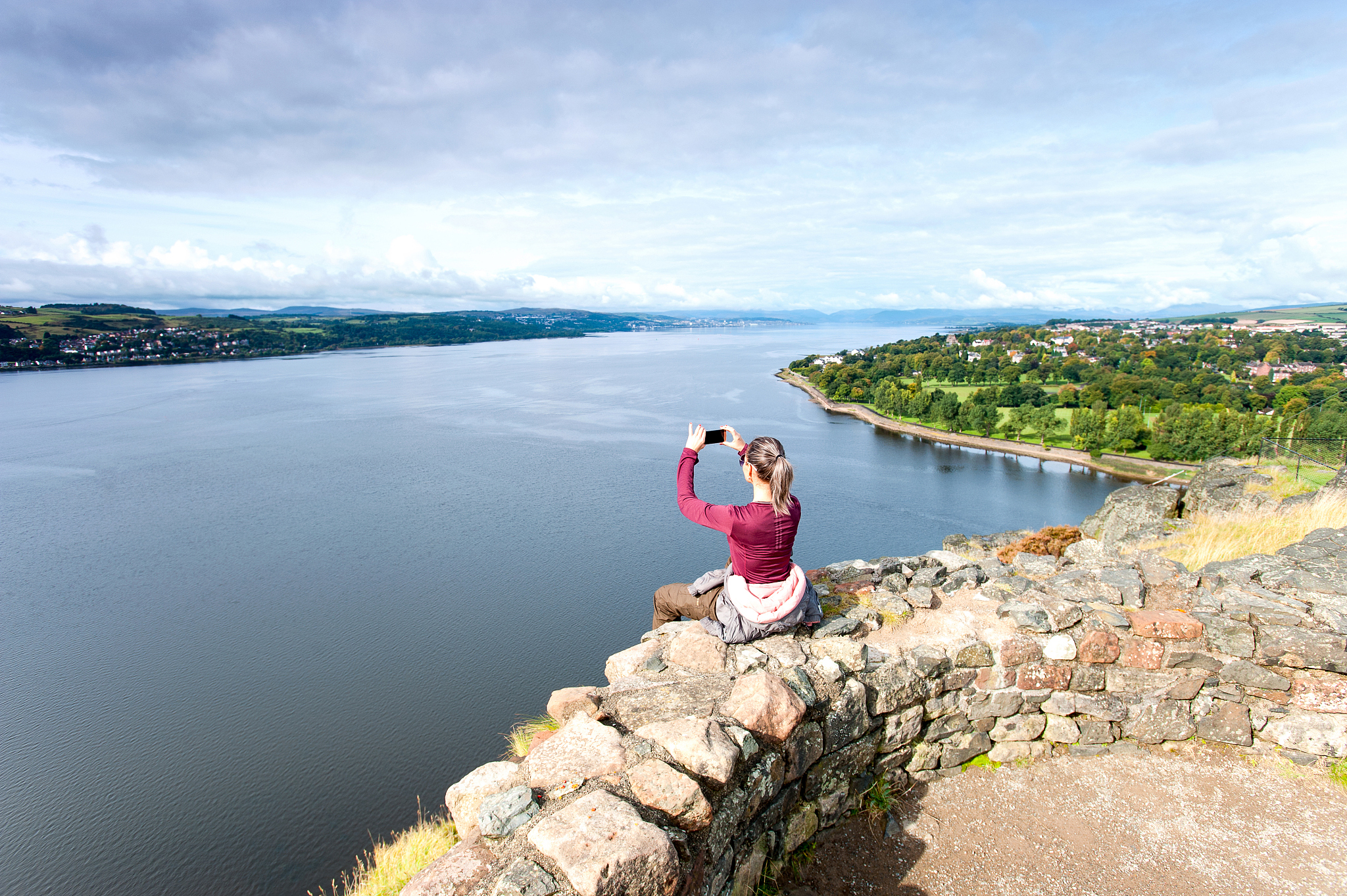woman traveller sitting on mountain top making picture by smartp
