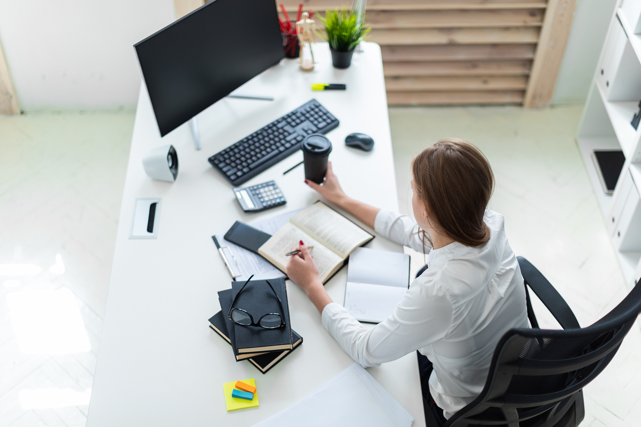 a young girl holding a glass of coffee and working in the office