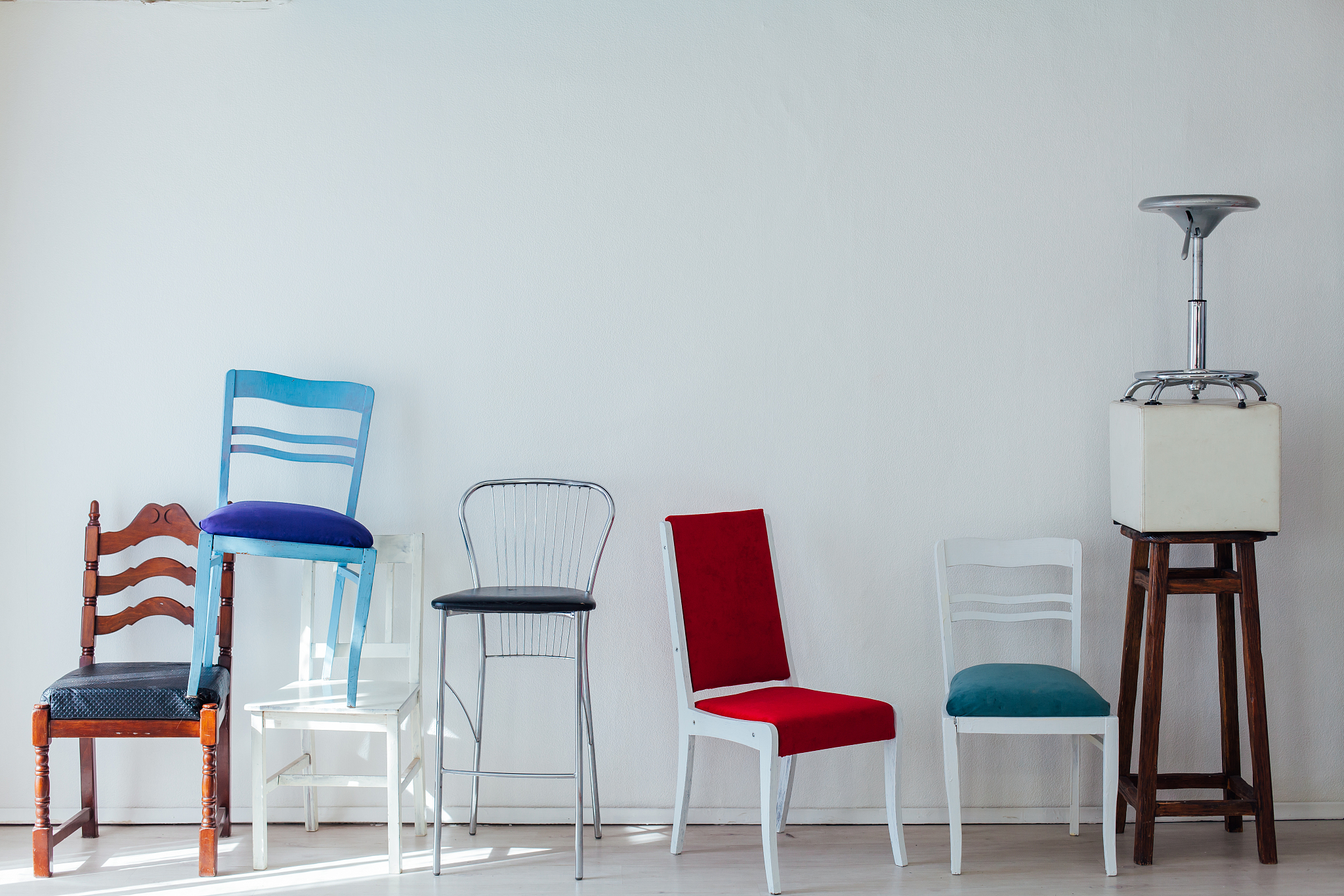 many different chairs of different colors stand at the white wal
